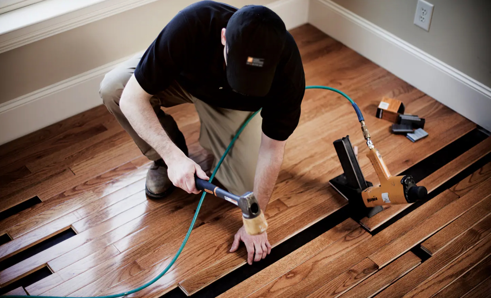 Hardwood floors installer installing prefinished hardwood using air nailer.