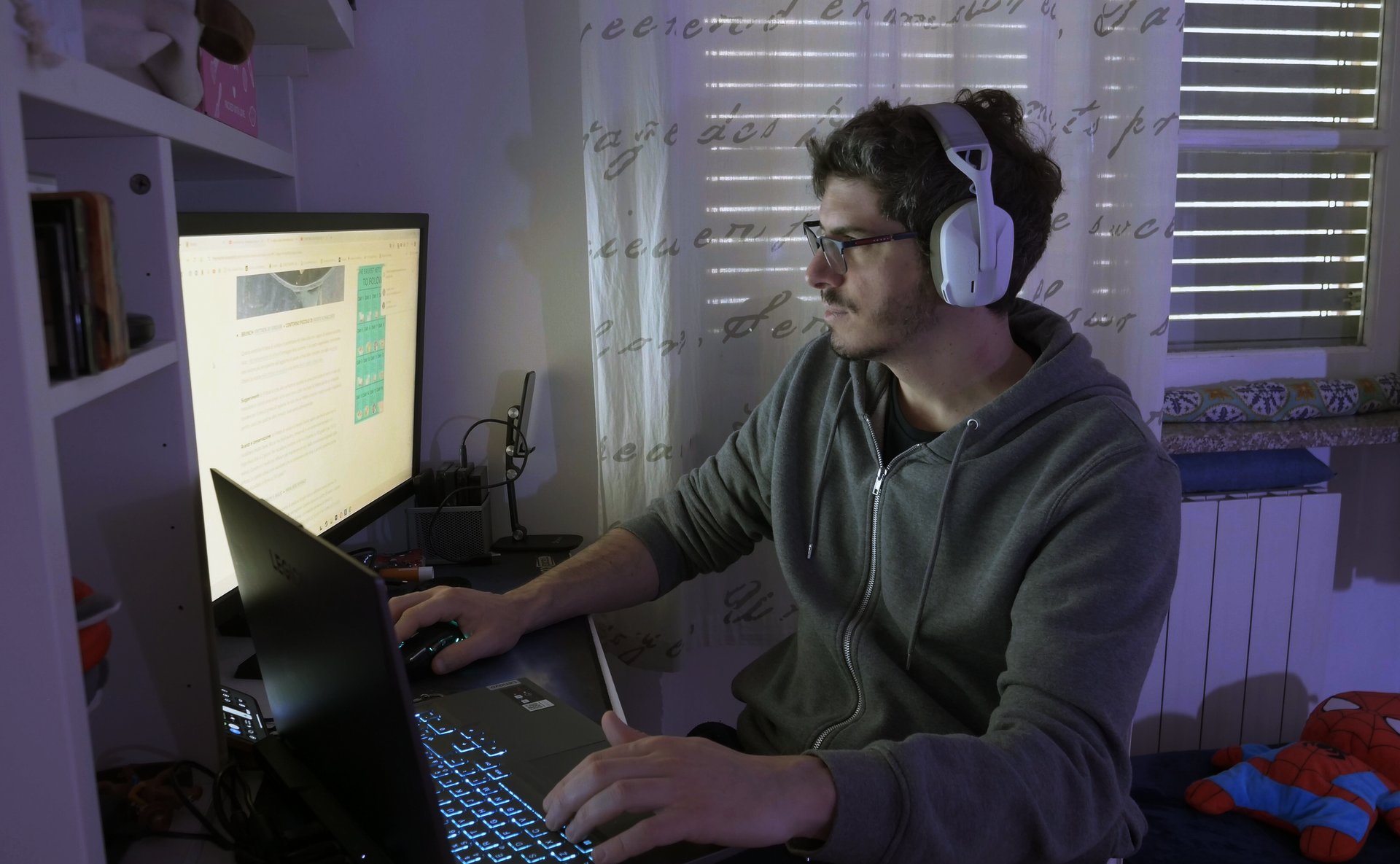 a man wearing headphones and headphones, sitting at a desk with a laptop