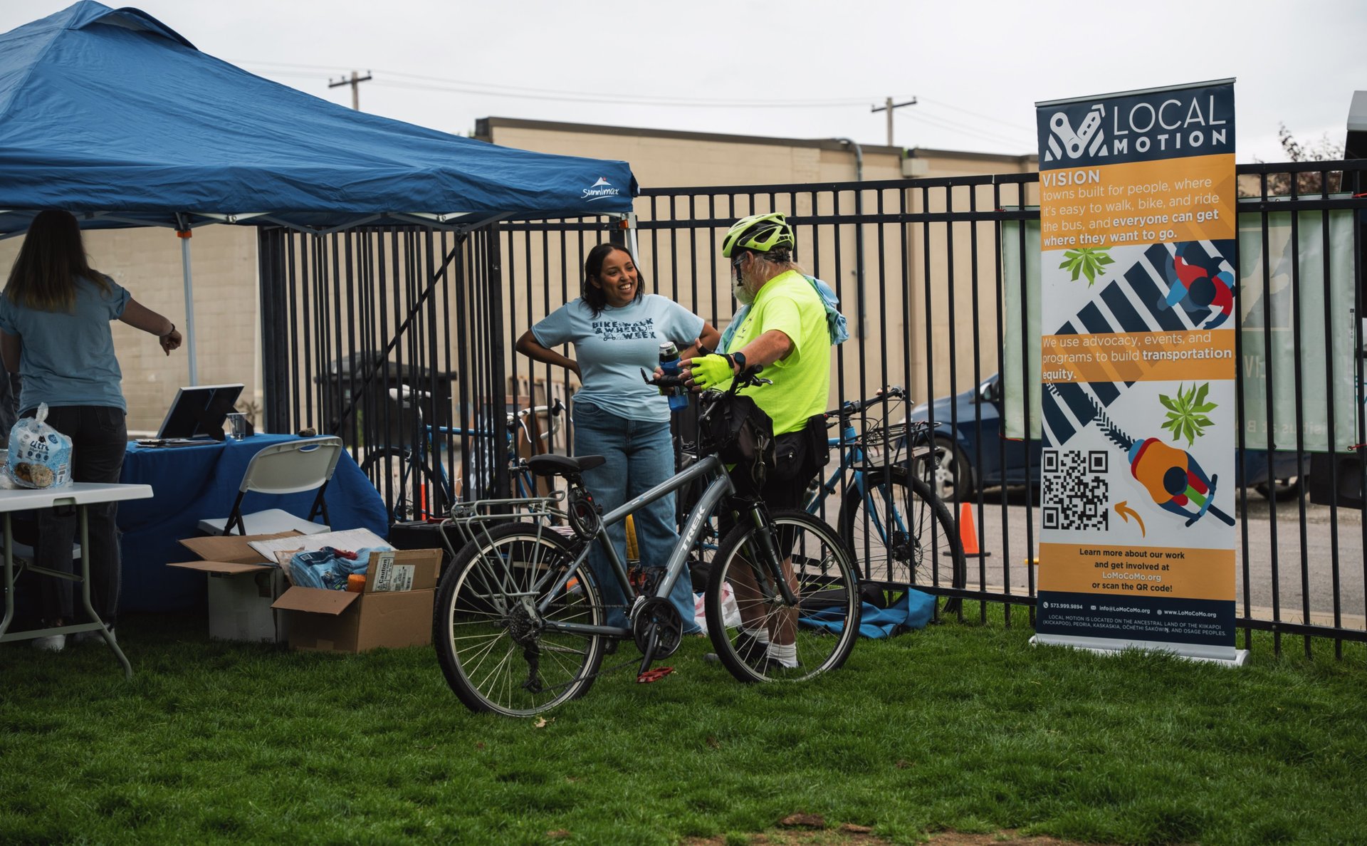 Man with his bike, speaking to a Local Motion staff member at their booth
