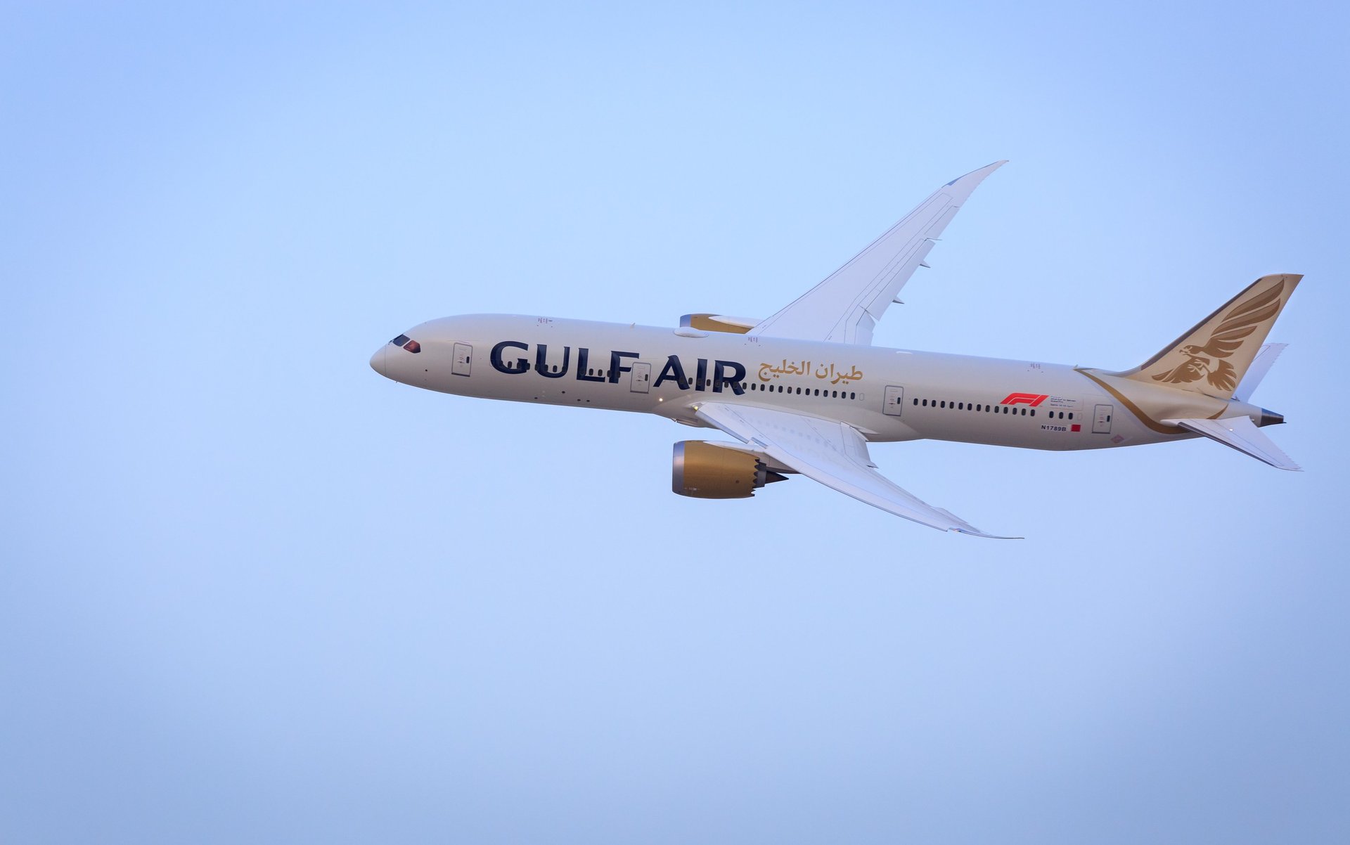 A white Gulf Air Boeing 787-9 Dreamliner passenger jet flying through a clear blue sky.