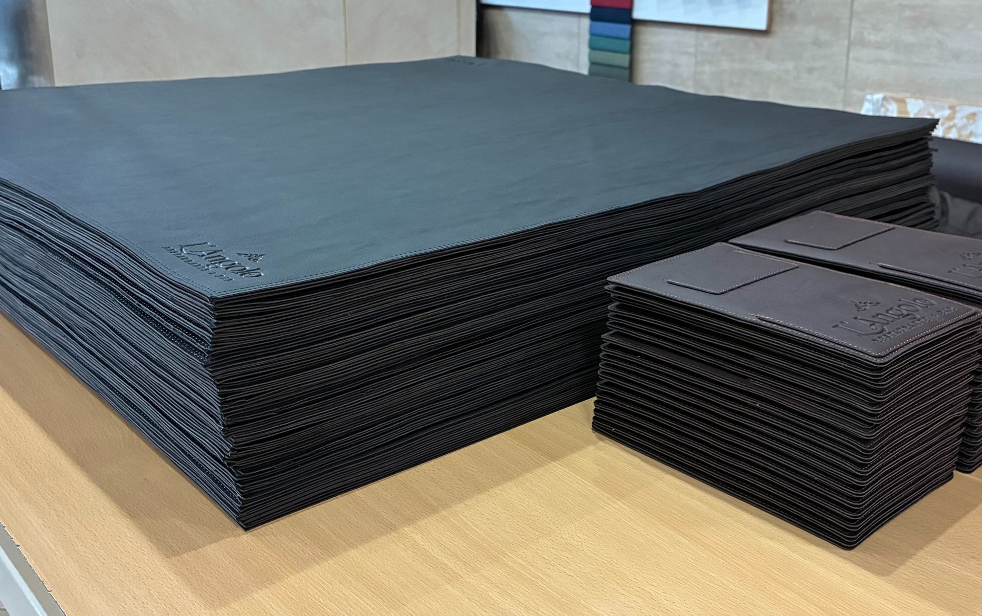 foto de una pila de cubremesas de similcuero y dos pilas de portacuentas de similcuero