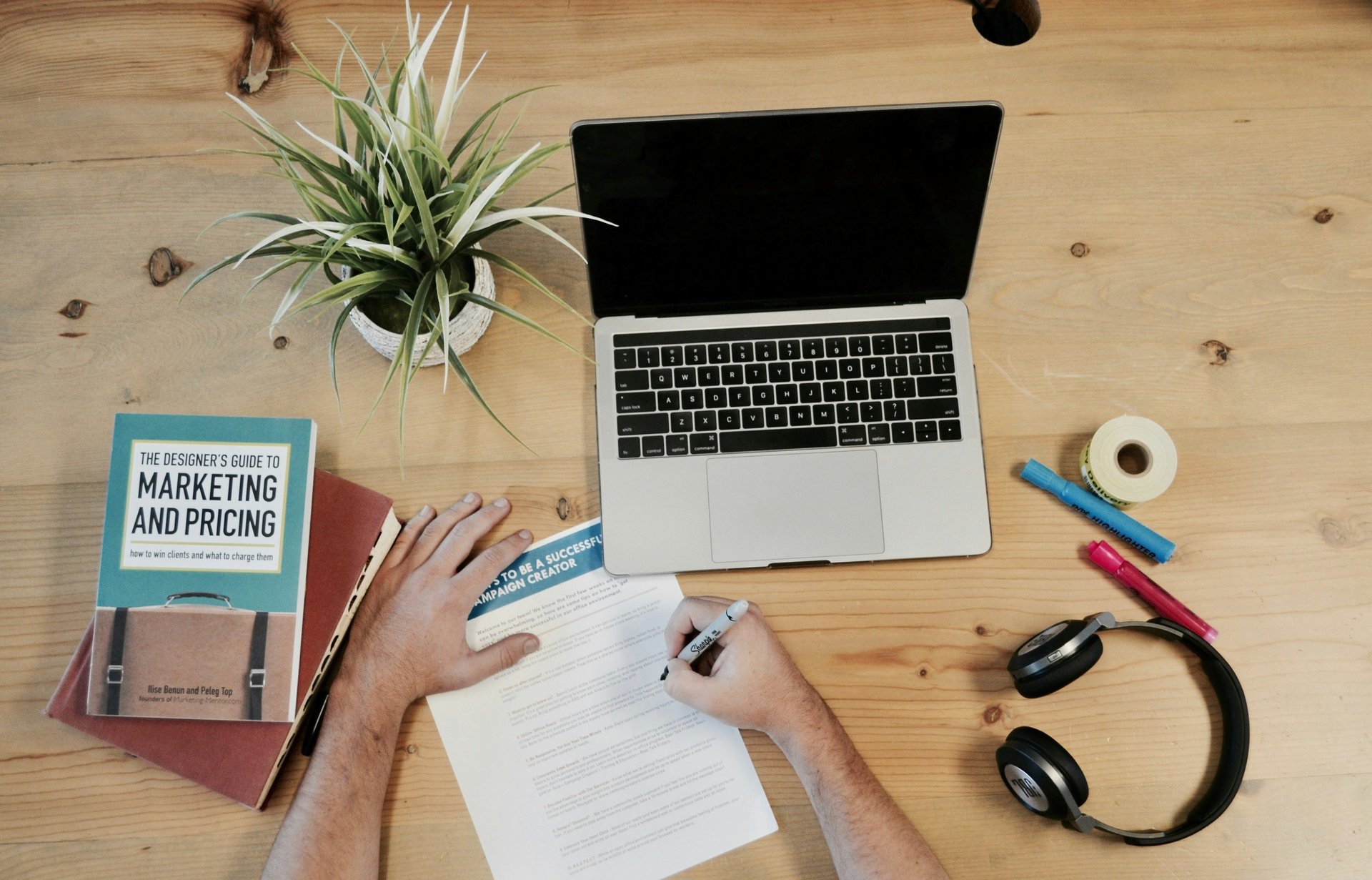 A person working on a paper with a computer and books nearby