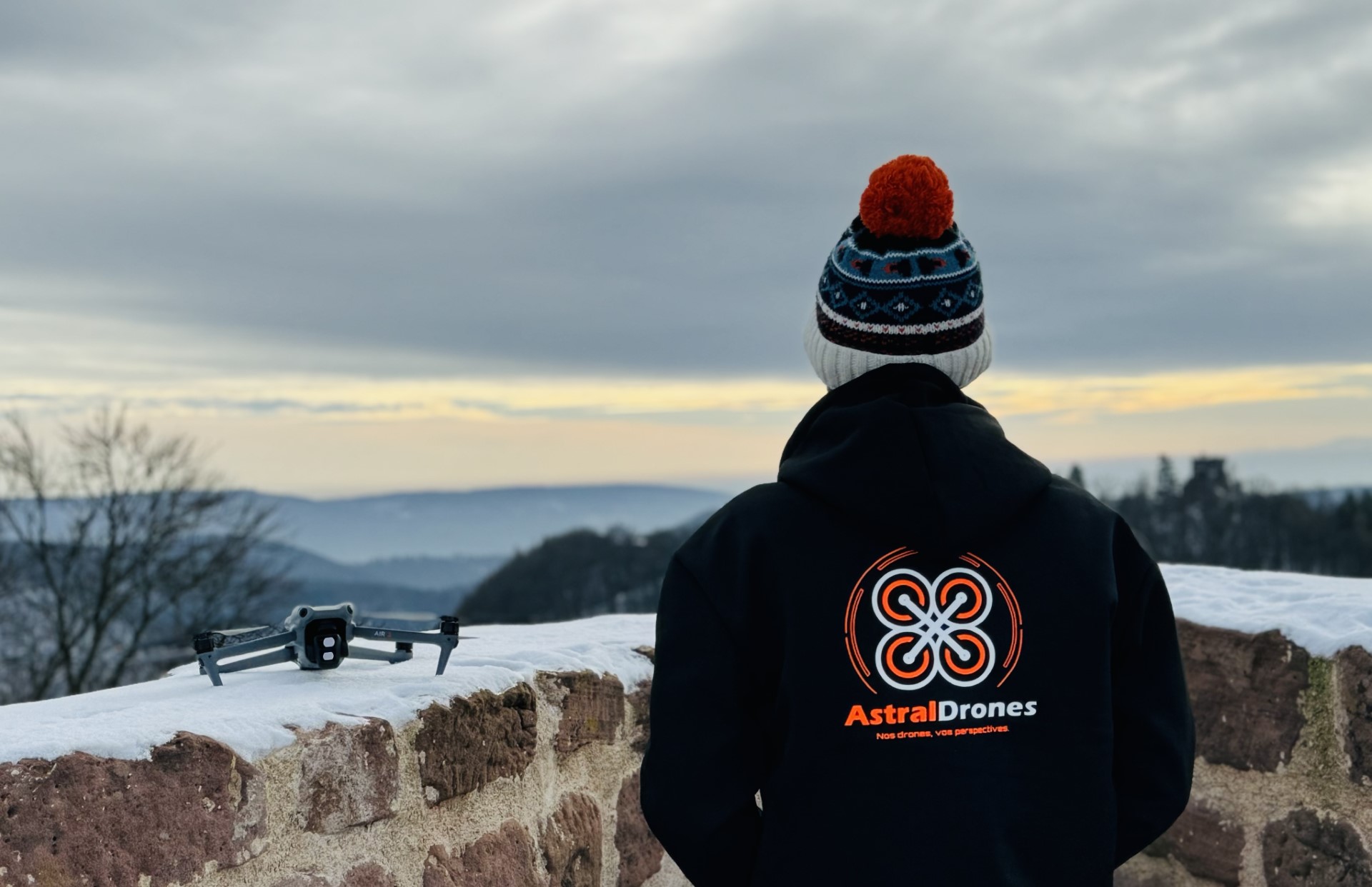 Télépilote Astral Drones avec un drone DJI Air 3 dans un paysage enneigé