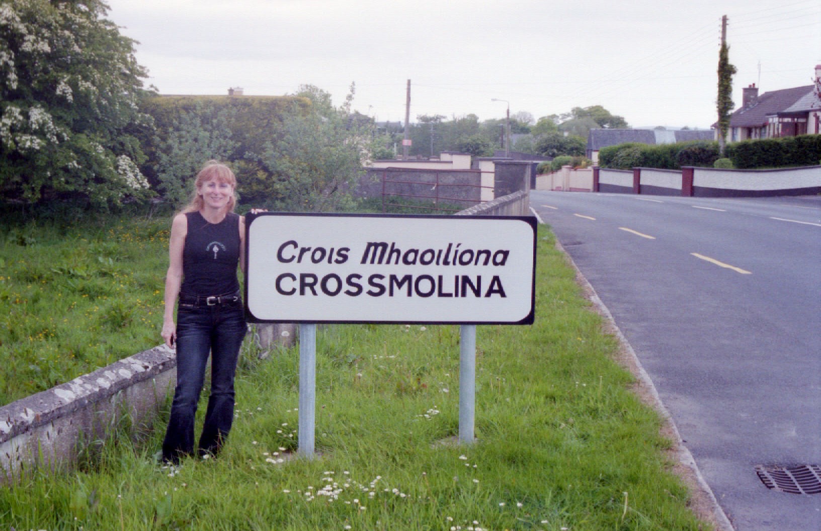 Annie of Crossmolina Band standing next to the welcome sign, County Mayo, Republic of Ireland.