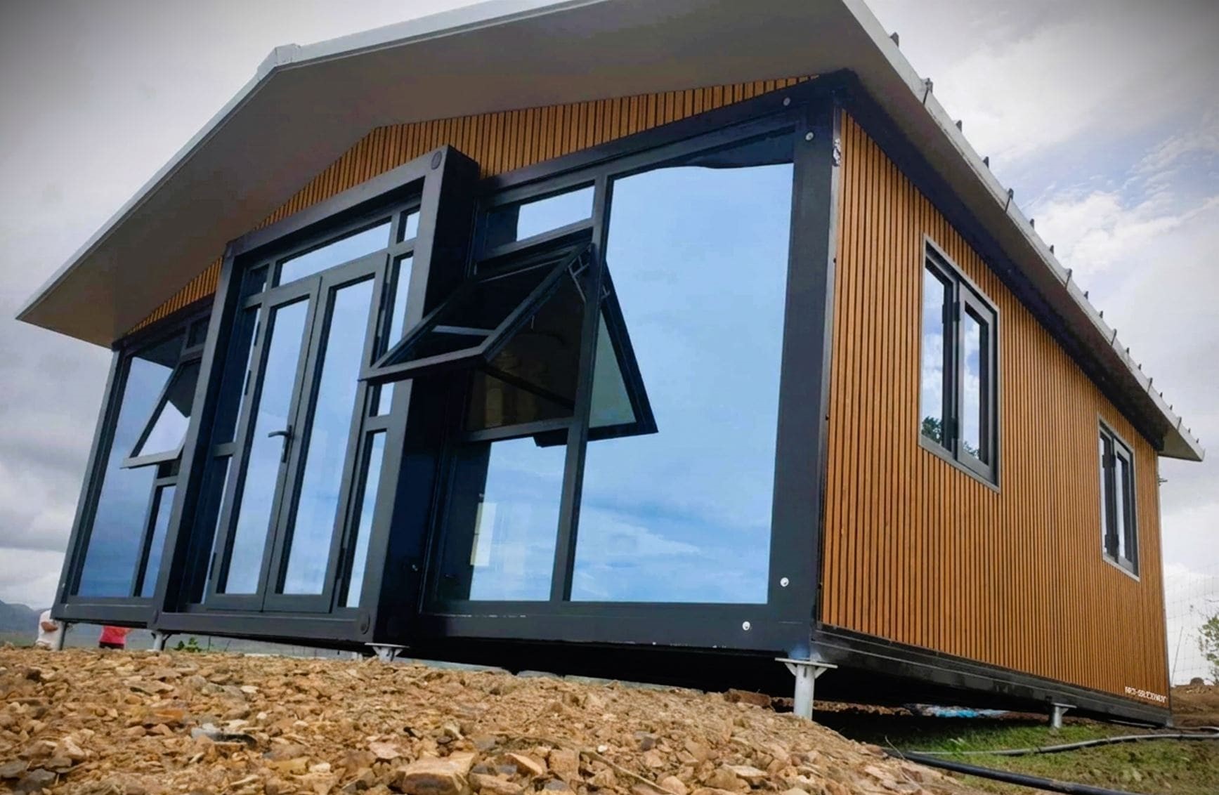 Tiny house modulaire moderne avec bardage bois et grandes baies vitrées.