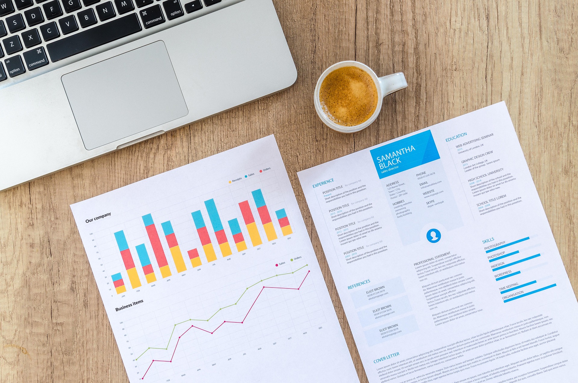 laptop and printed charts on a wooden desk