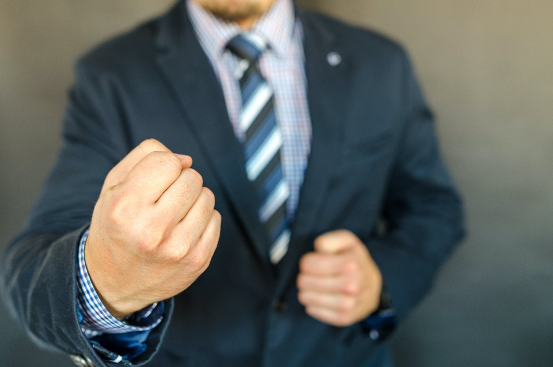 A man in a suit clinching his fists.