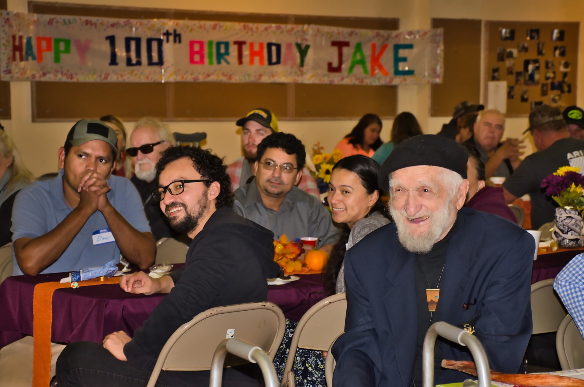 a group of people smiling and sitting at a table with food