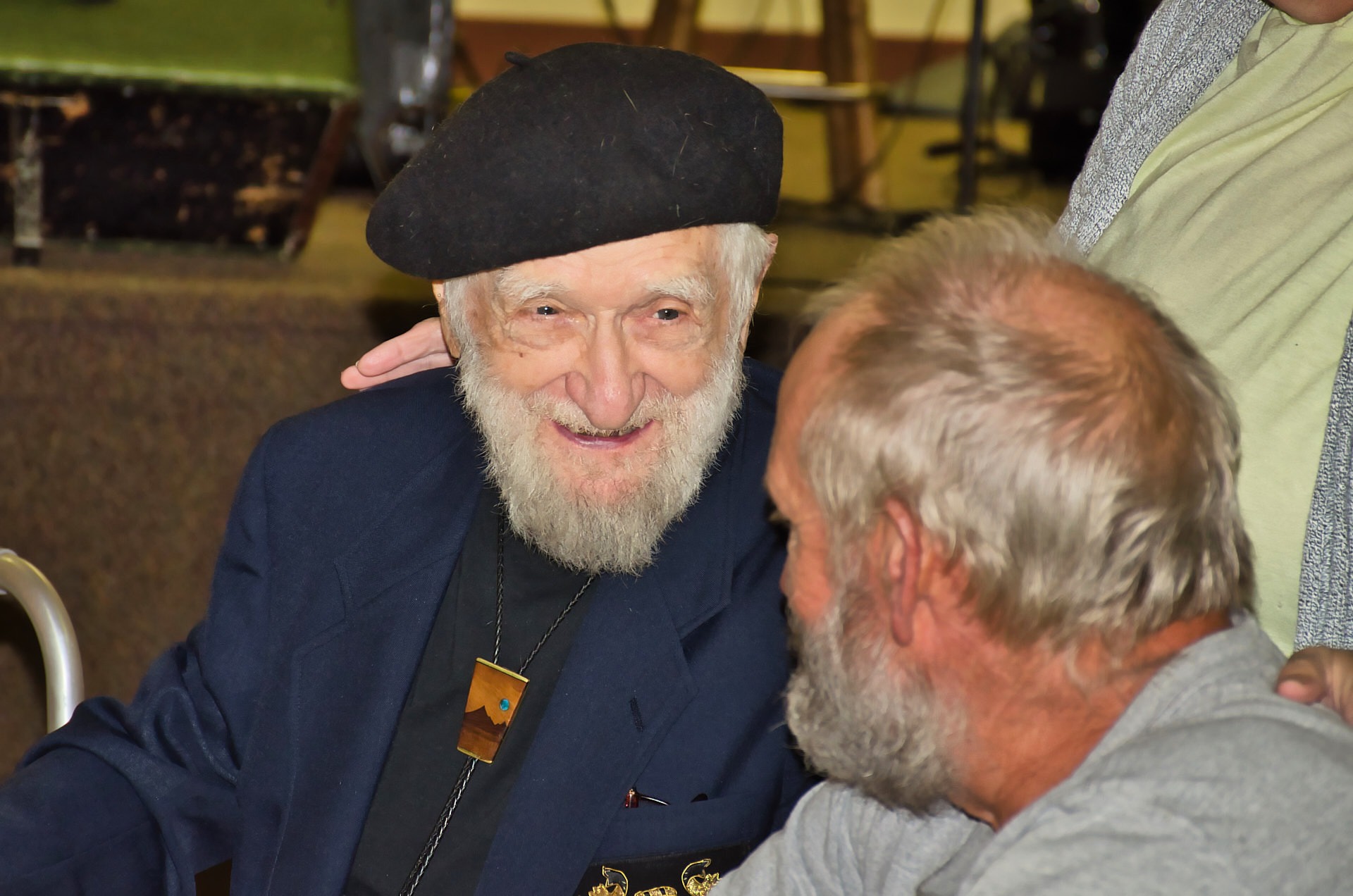a man with a white beard and a hat smiling at his friend