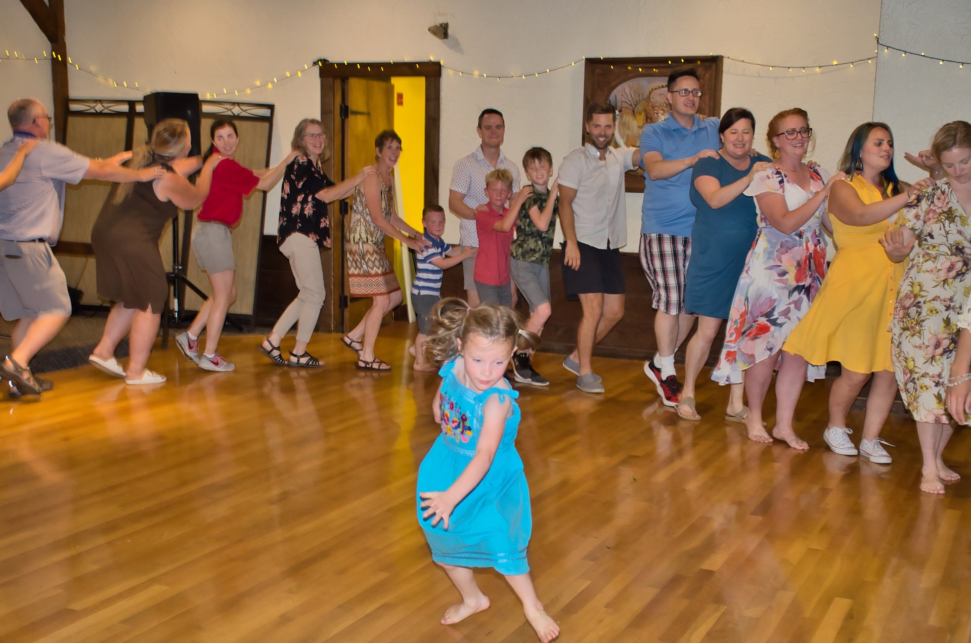 a young girl in a blue dress dancing in front of a group of people