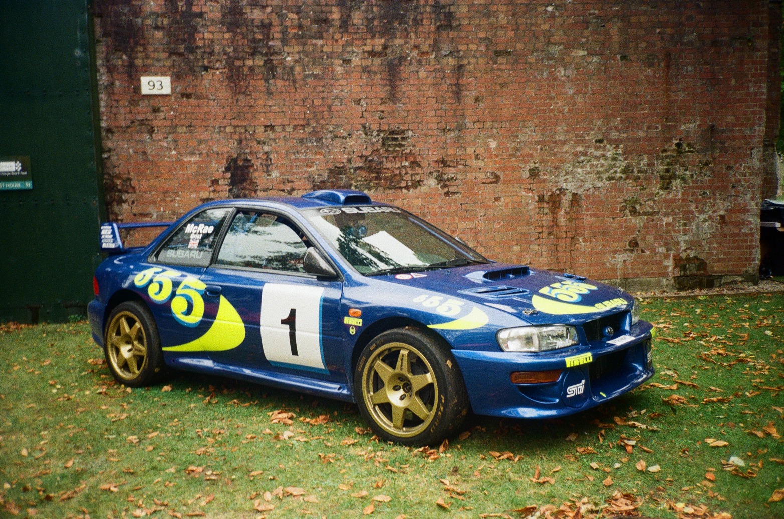 a Subaru Impreza rally car parked in front of a brick building
