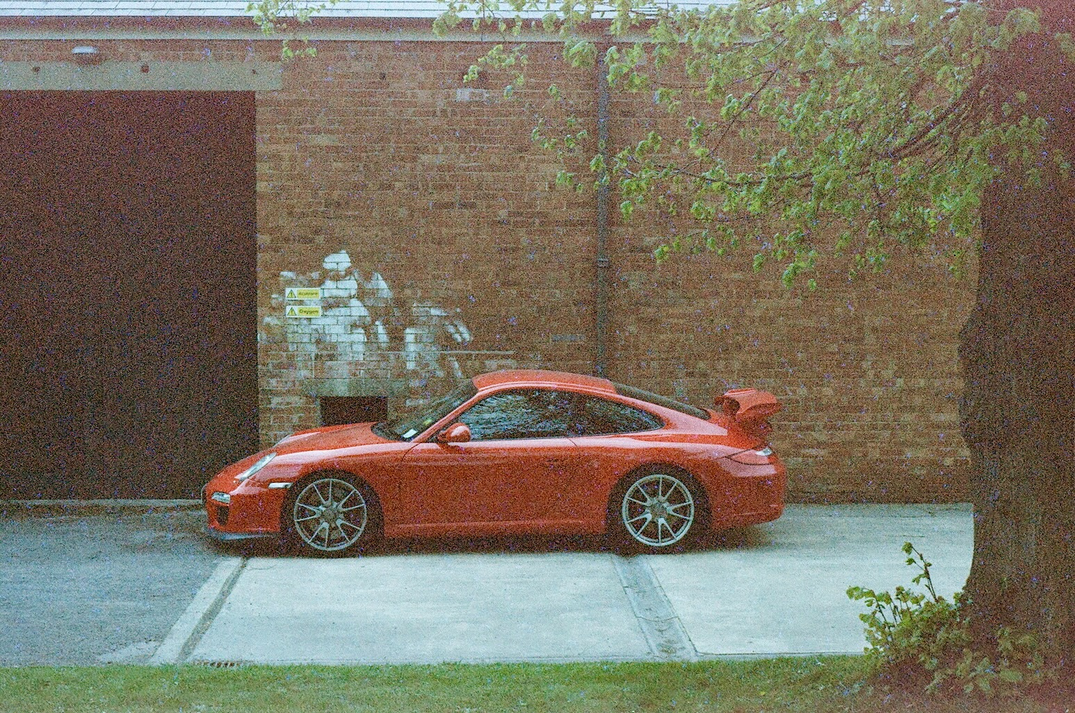 a red Porsche parked in front of a brick building