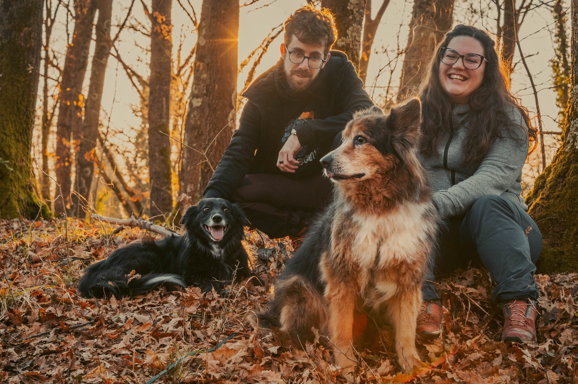 famiglia di due persone che sorridono con due cani al tramonto