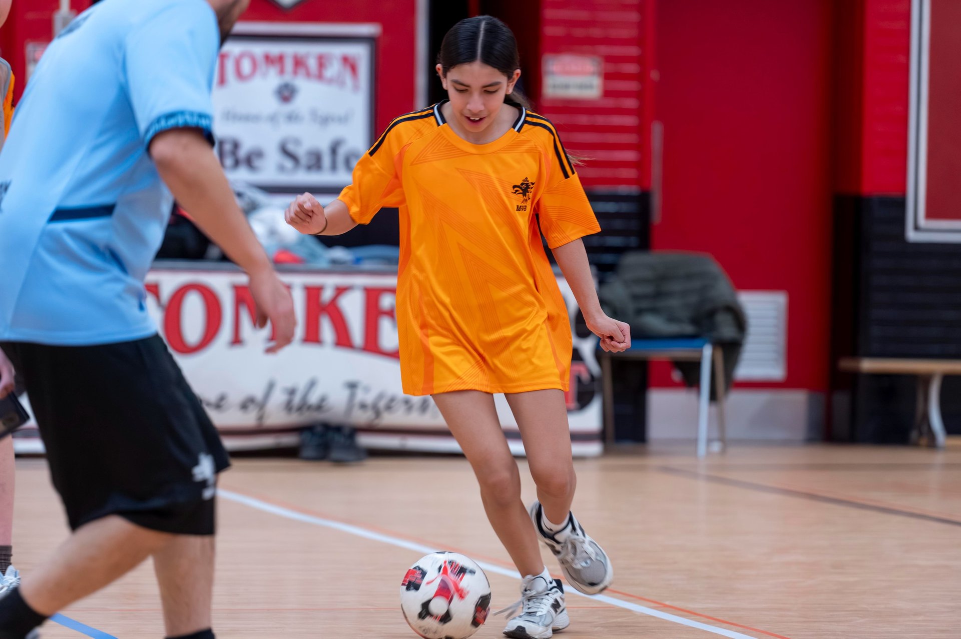 A young girl in a MVB FC Jersey dribbles a soccer ball indoor Mississauga Soccer School Practice