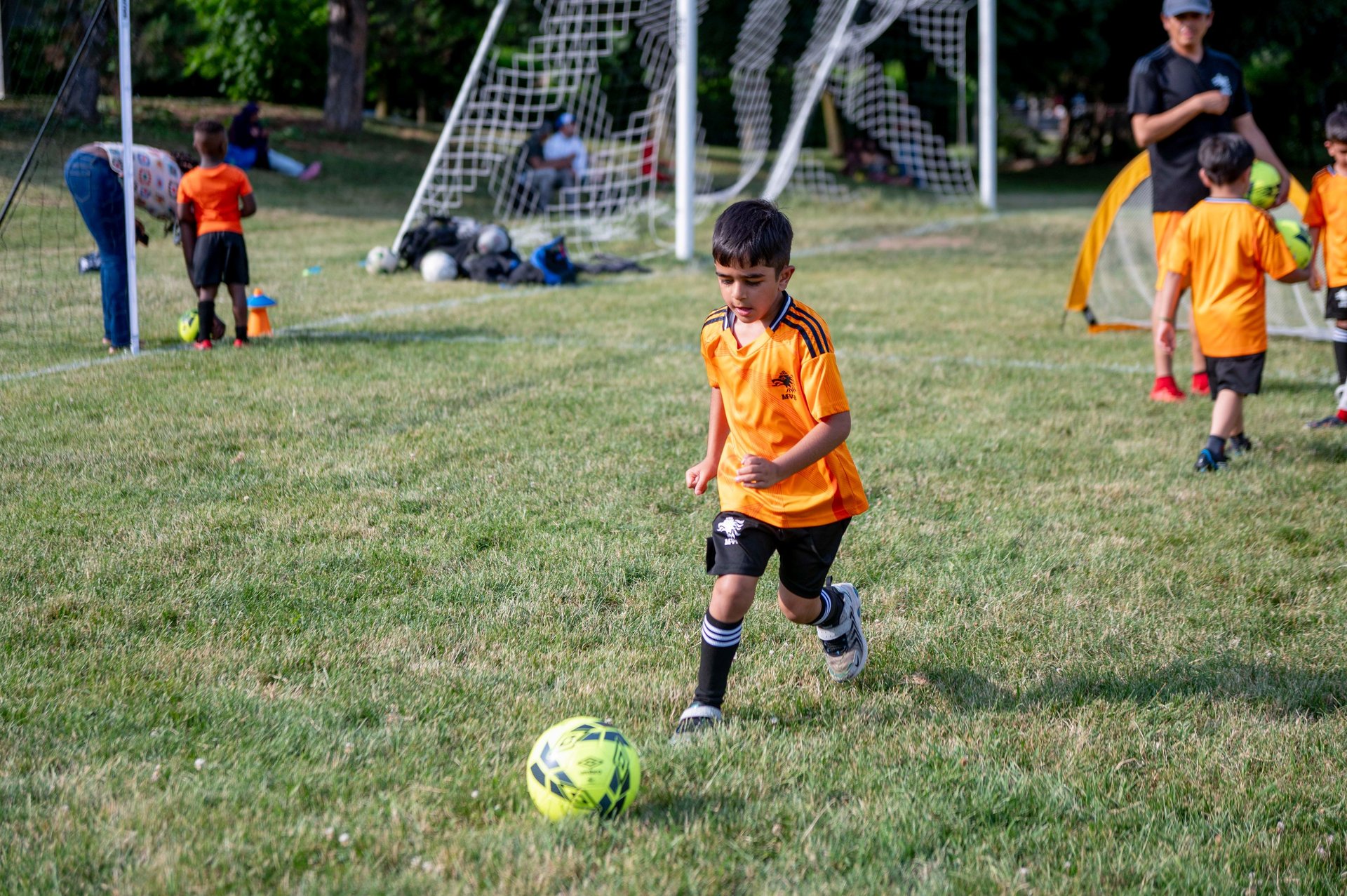 A young boy in an MVB F.C. jersey dribbles a soccer ball during a youth soccer practice  Mississaga