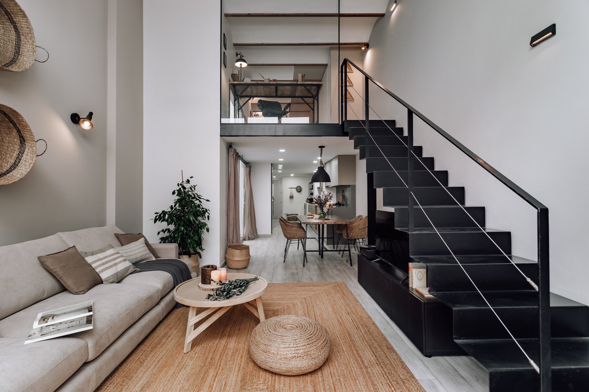 Dining area with iron staircase and wooden dining table, natural textiles and colours design