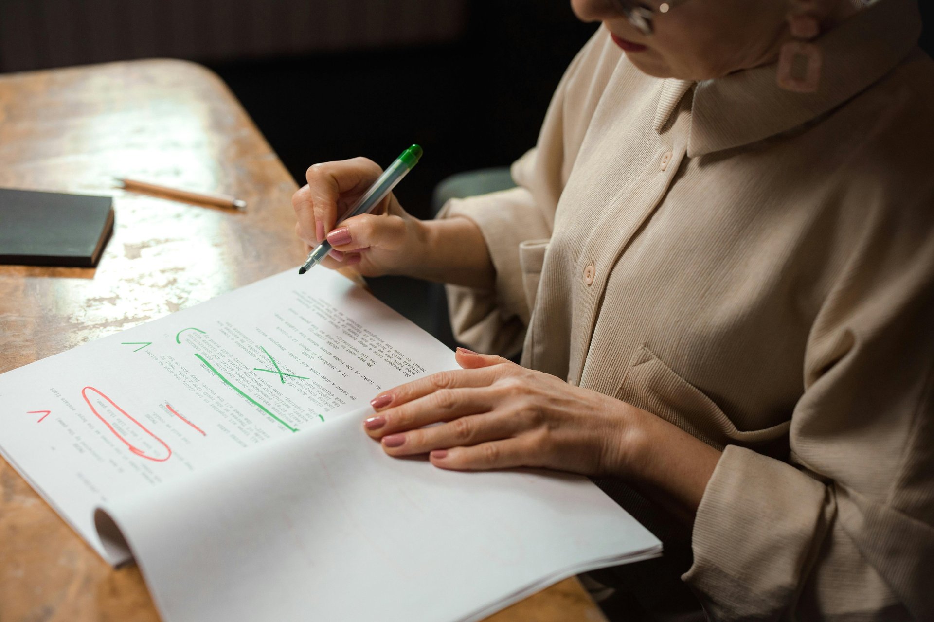 a woman in a brown shirt is writing and editing on a piece of paper