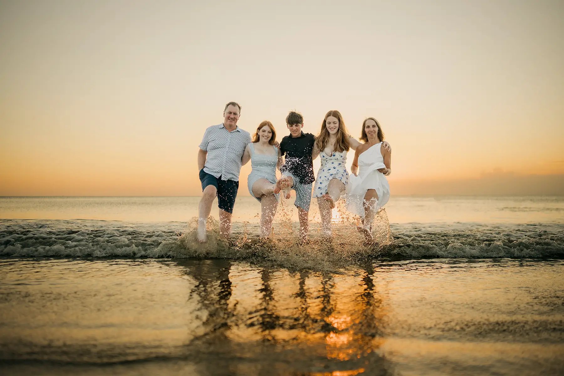 Family playing together in the shallow sea during a sunset family photography session at Jimbaran Beach Bali
