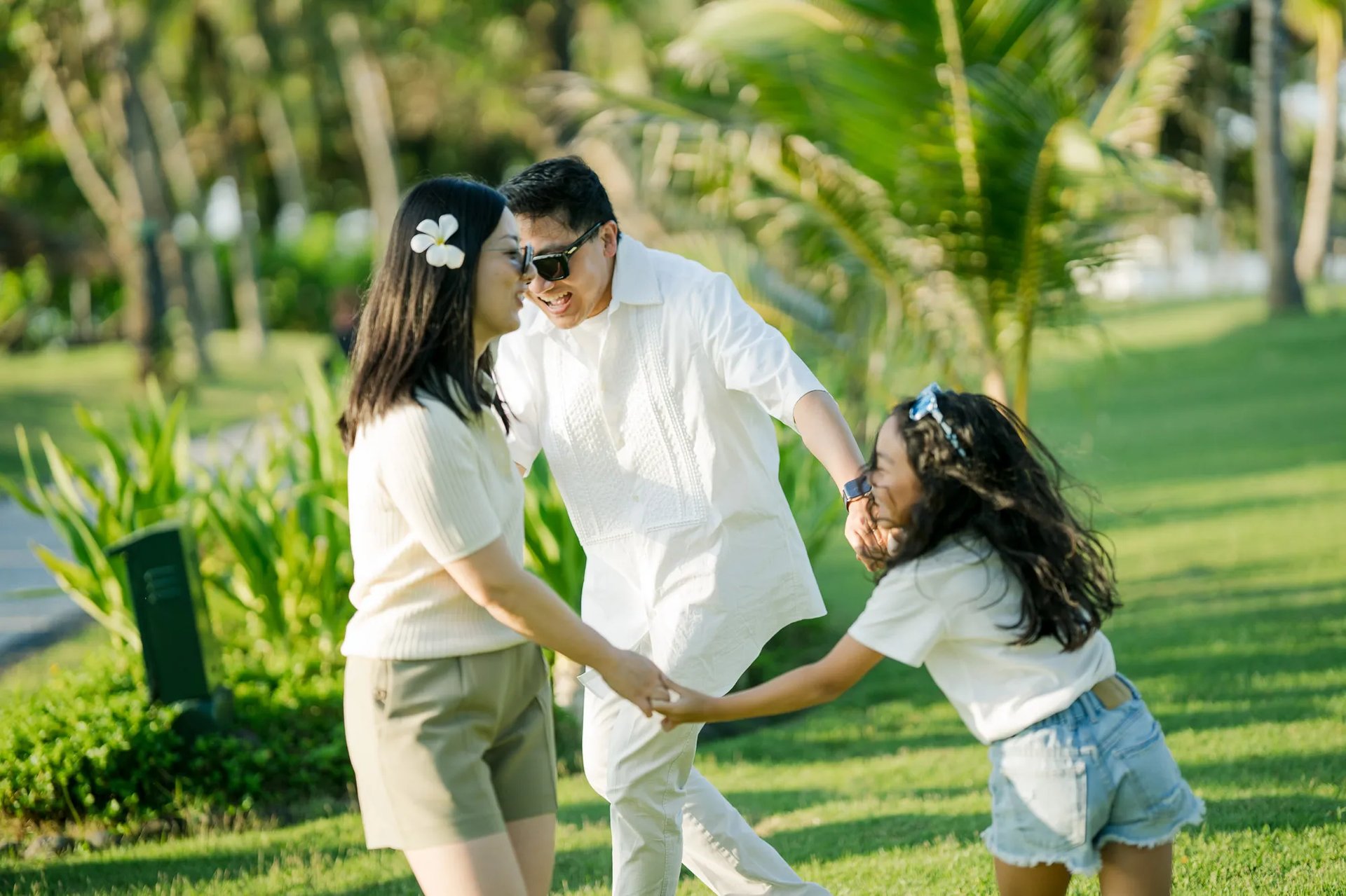 Parents and daughter sharing a playful moment in the tropical gardens of InterContinental Bali Resort