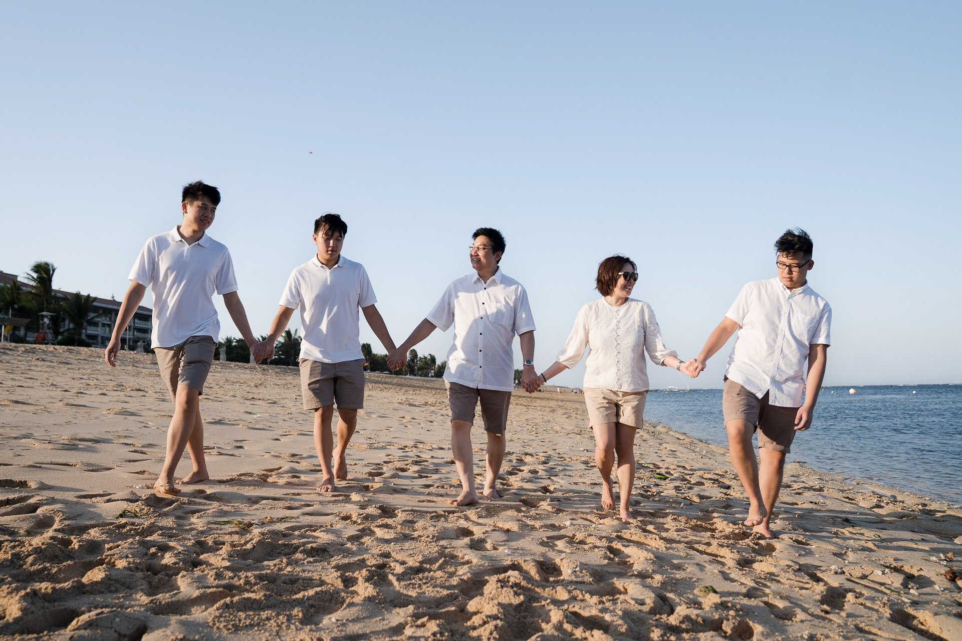 Family walking together on the beach during a family photography session at The Mulia Nusa Dua Bali