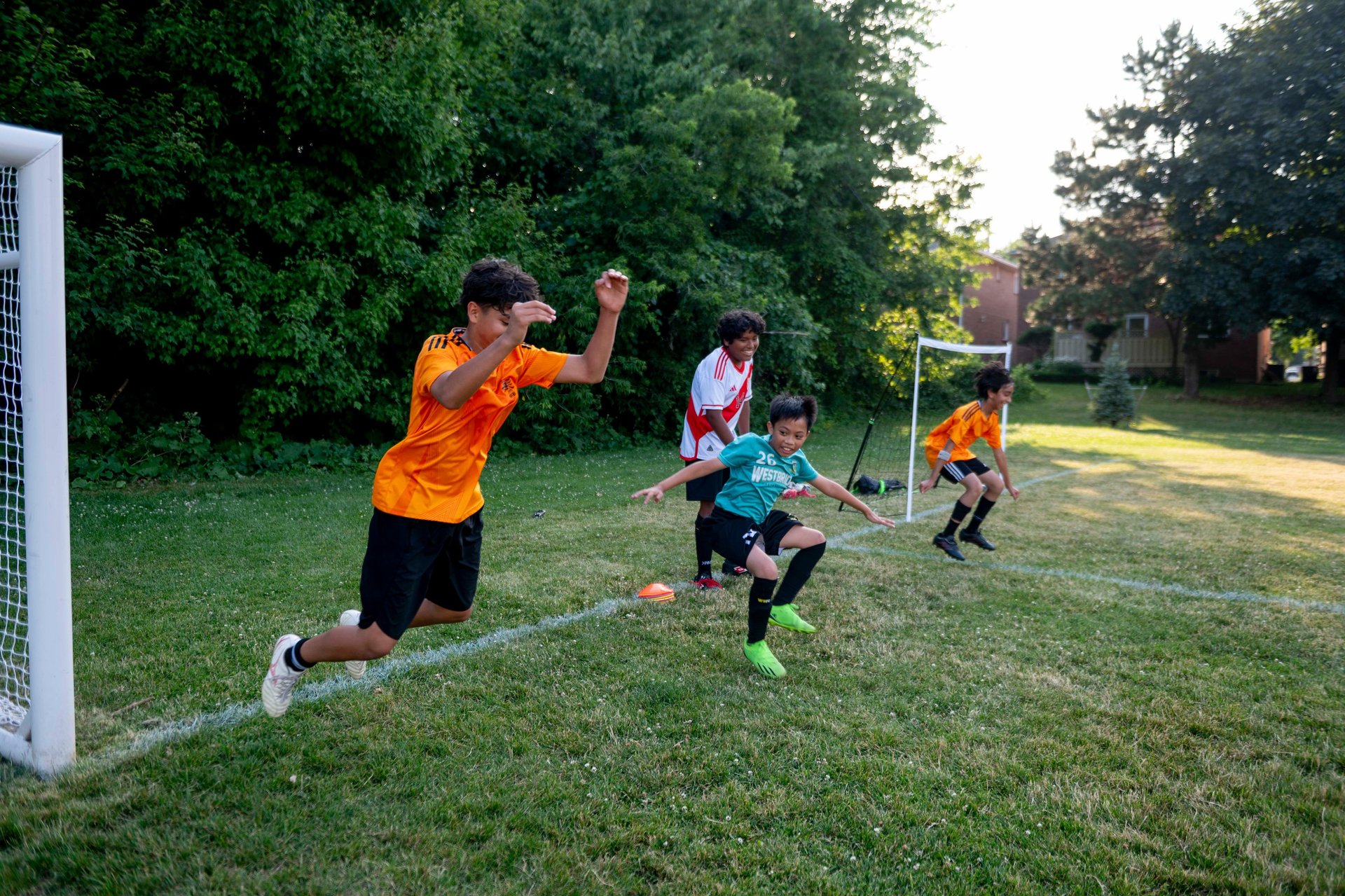 Young boys practicing soccer drills, jumping on a green grass field during MVB FC Soccer training.