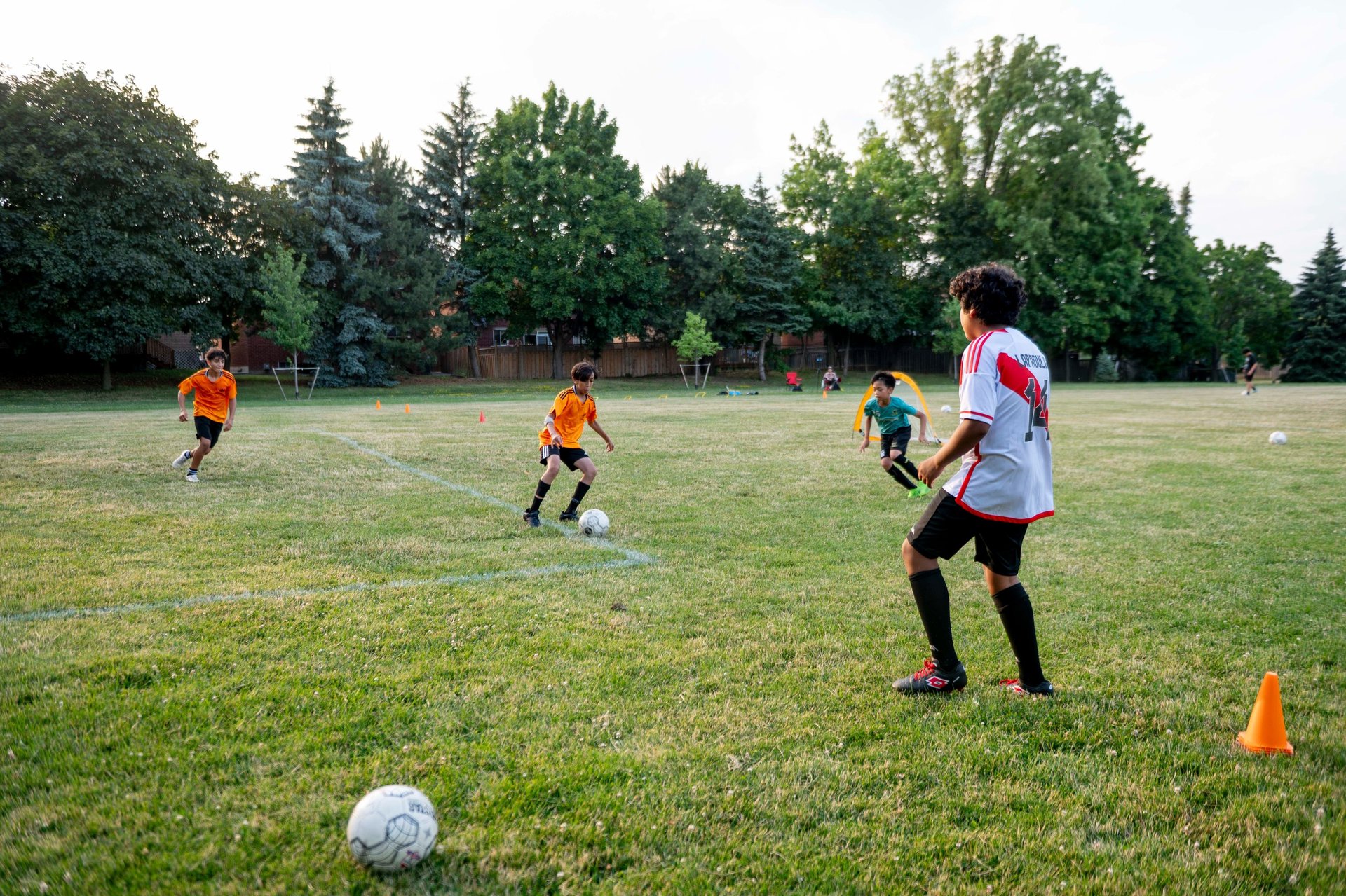 Young boys playing a soccer match on a grassy field during outdoor MVB FC soccer class Mississauga