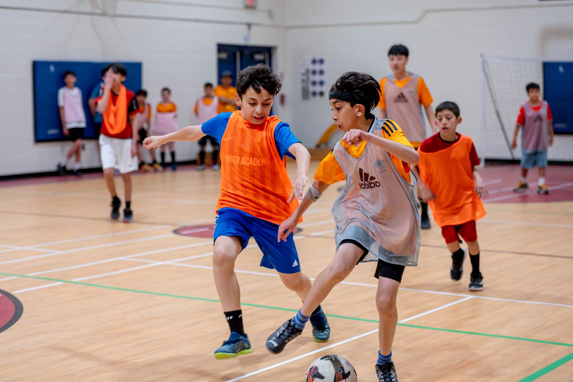 Youth players competing in an indoor soccer match during a MVB FC soccer class