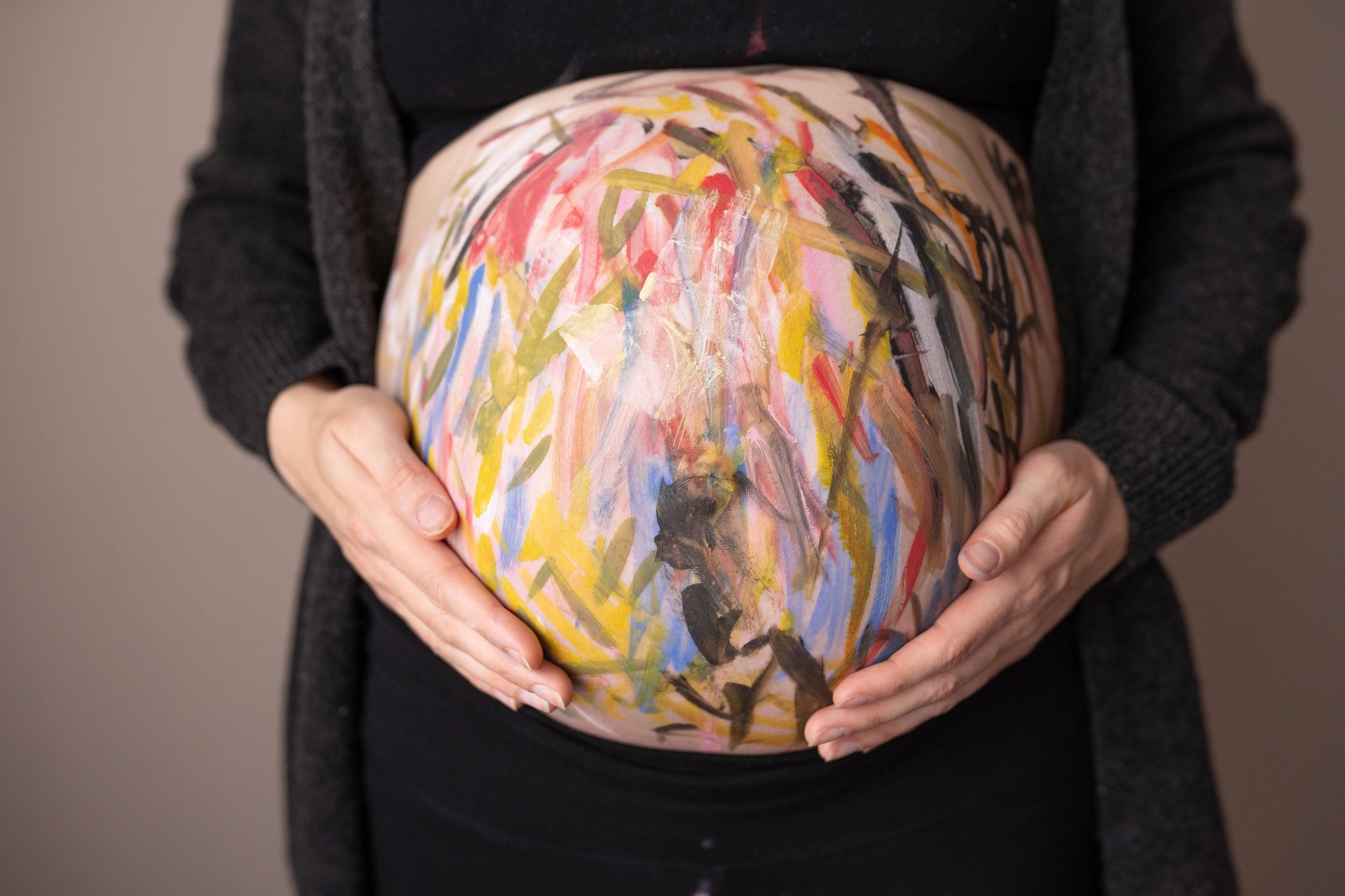 Babybauch mit bunter Farbe angemalt als Bellypainting