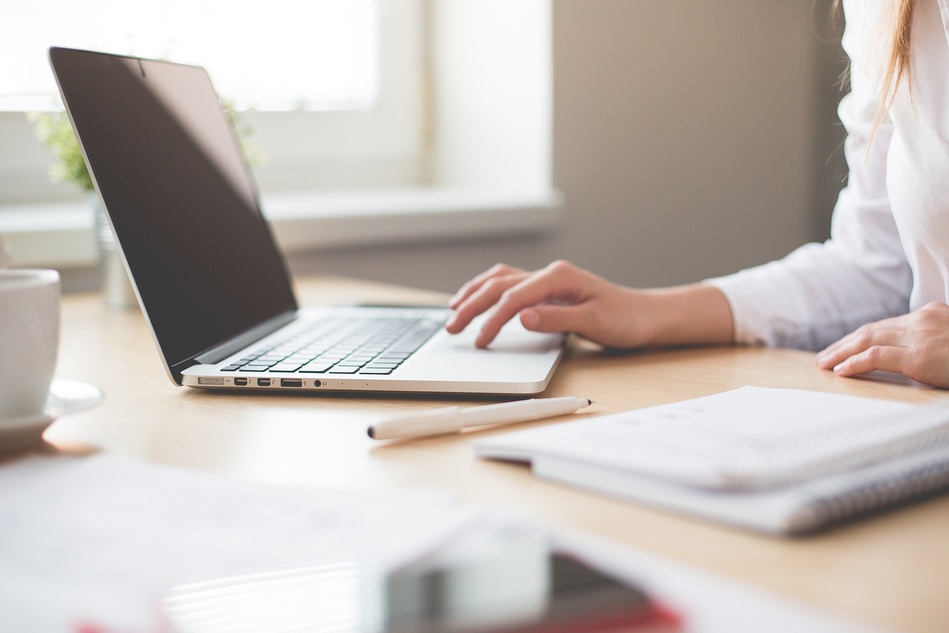 a woman sitting at a desk with a laptop and a notebook