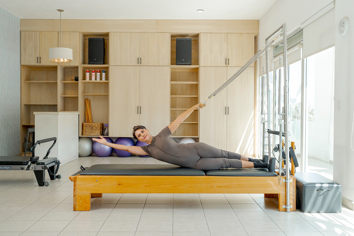 Woman performing a side-lying torso stretch using the springs of a Cadillac Pilates unit.