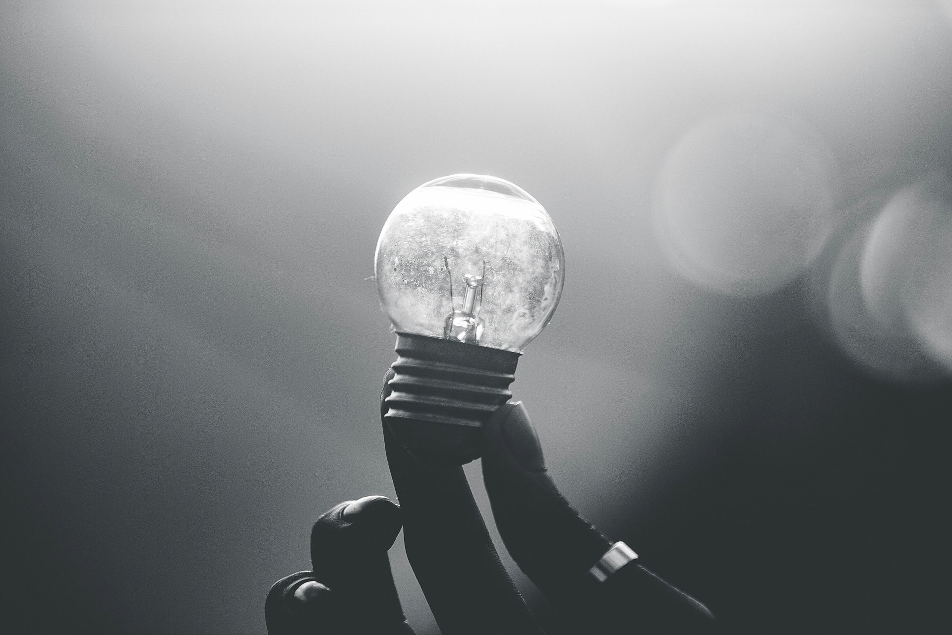 black and white photo of a person holding a light bulb in the light