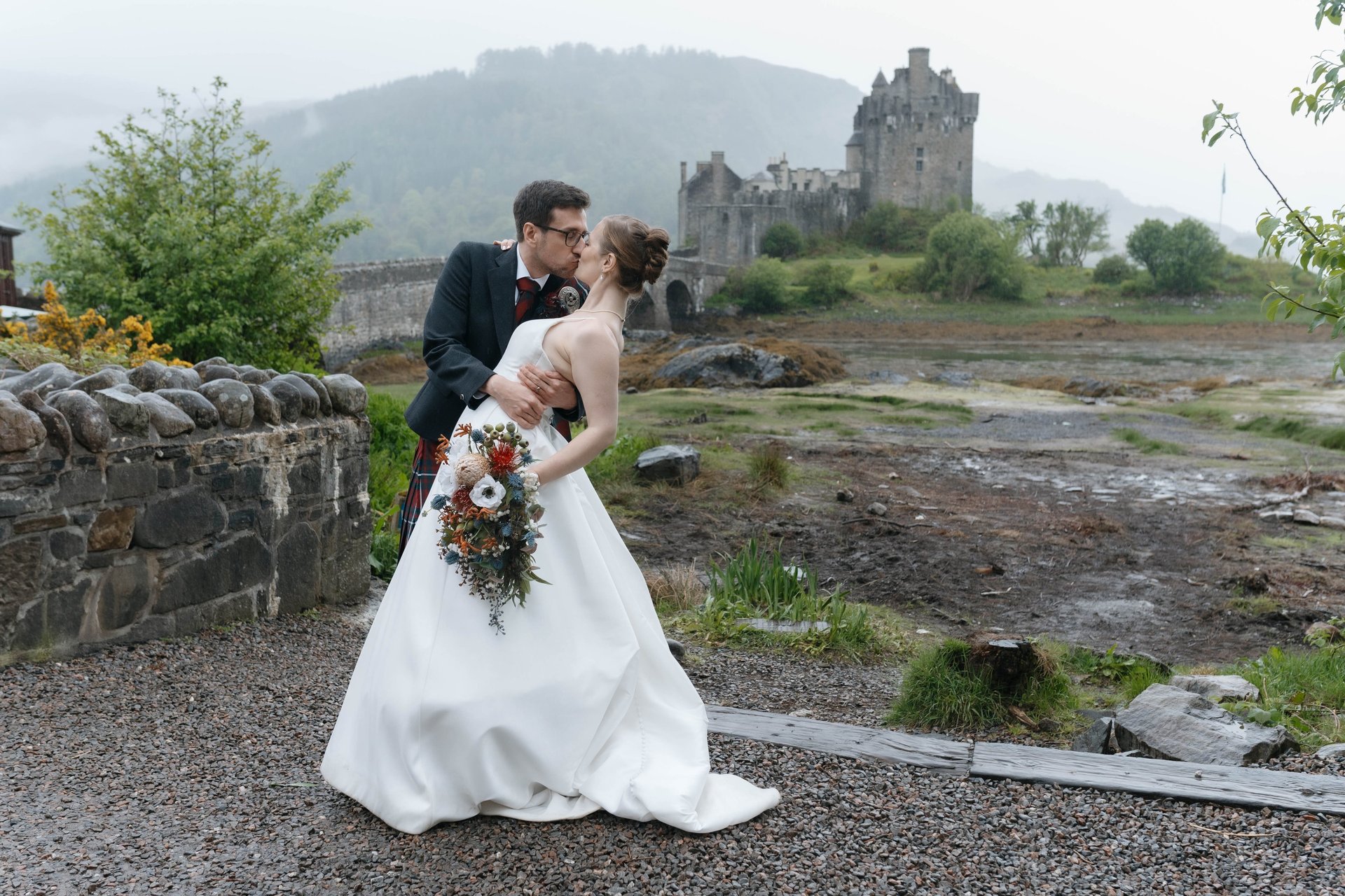 A bride and groom kissing during an elopement at Eilean Donan Castle in the Scottish Highlands.