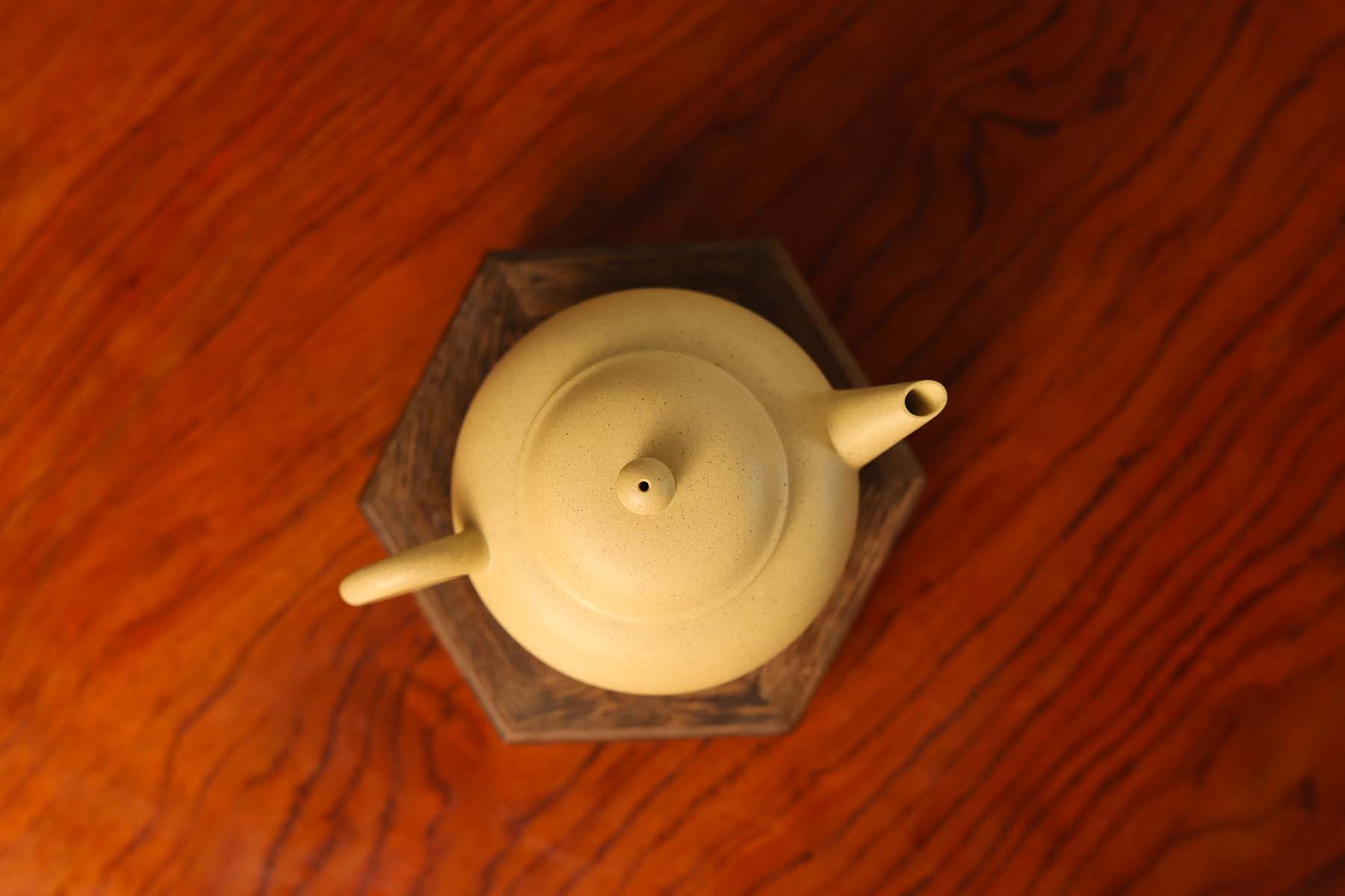 Overhead view of a light yellow teapot placed on a wooden stand