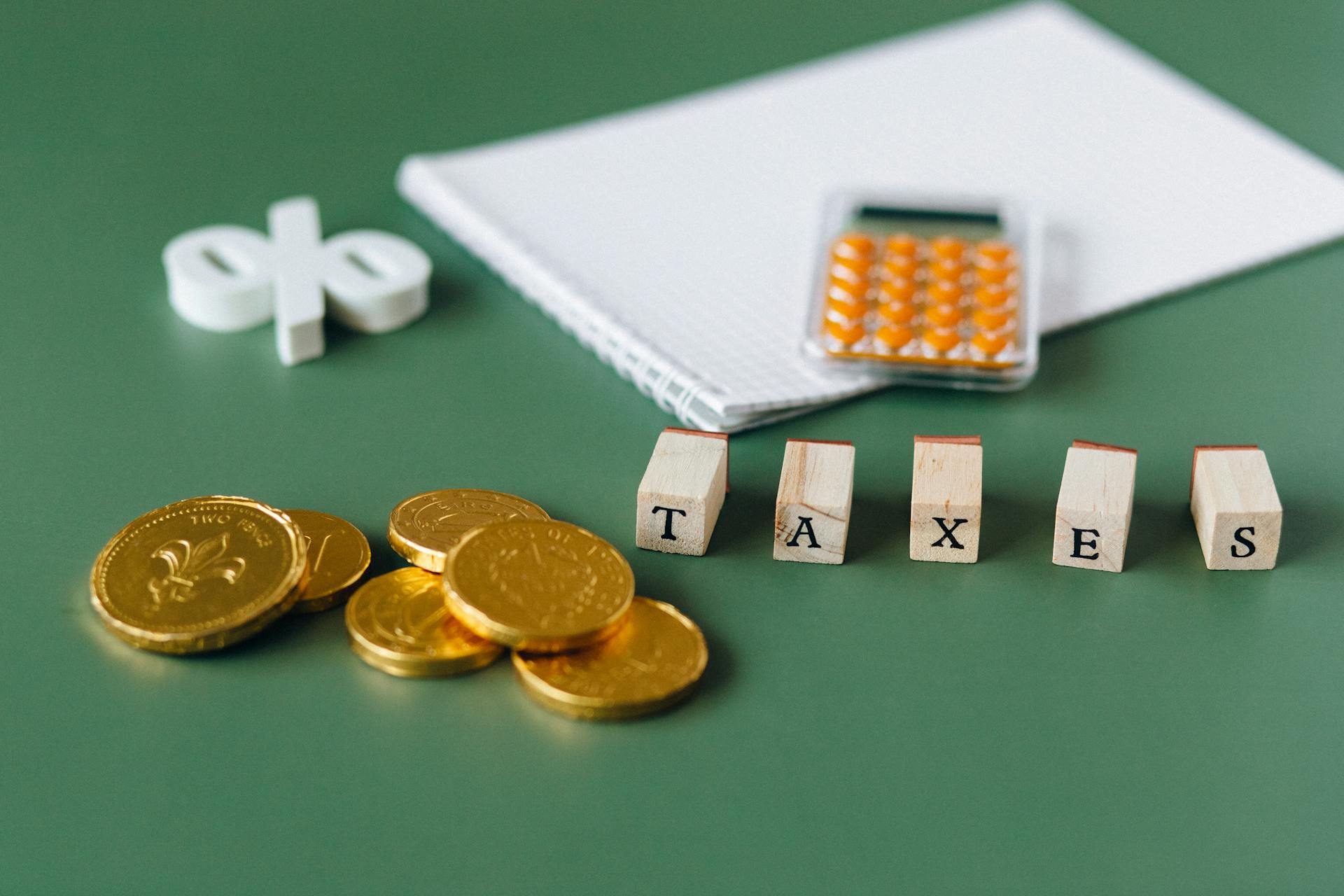 gold coins, calculator and word taxes show gold ira taxes and learning potential tax benefits