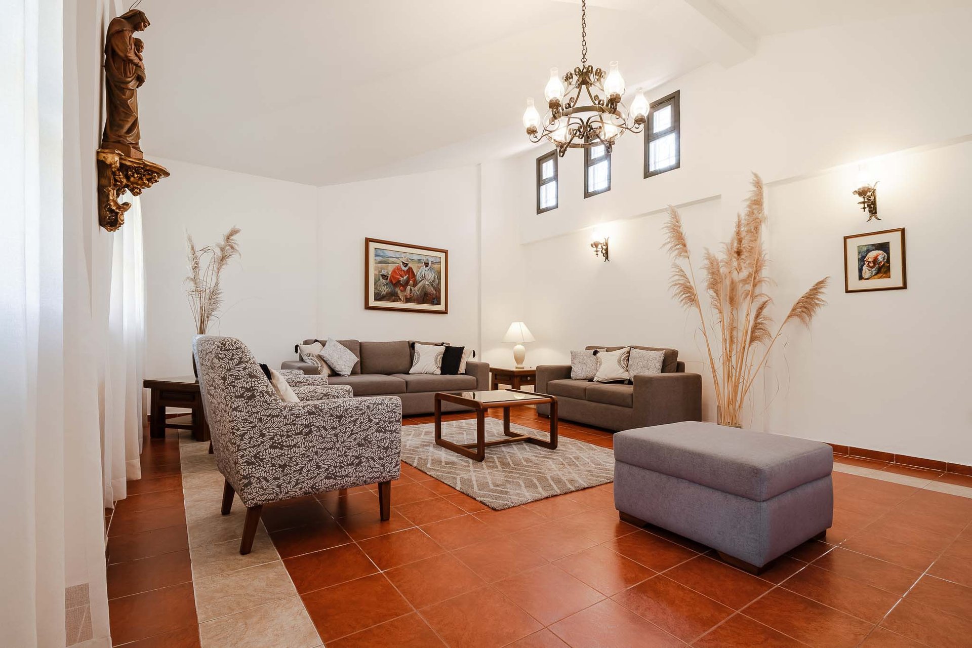 Habitación interior amoblada y decorada con pinturas, candelabro  plantas con sillones cafés AirBnB en Quito, Ecuador