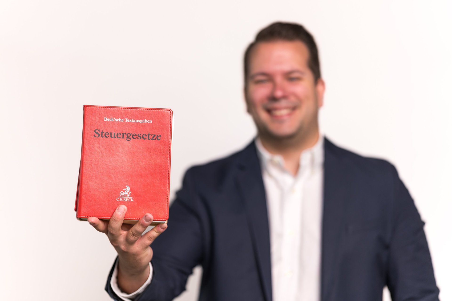Steuerberater Niklas Schüller hält das Steuergesetzbuch in der Hand