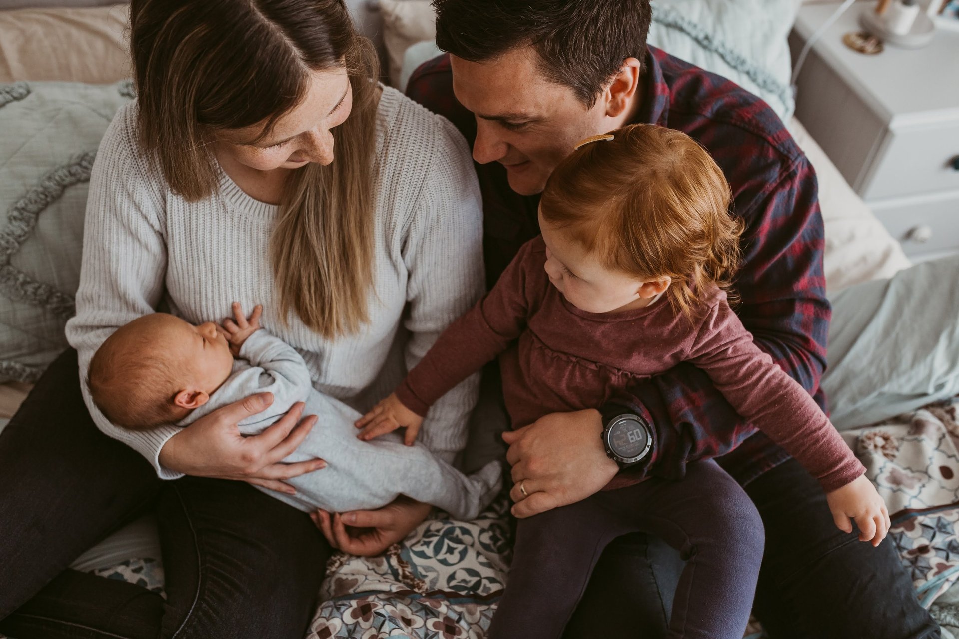 a man and woman holding girl and a baby in a bed