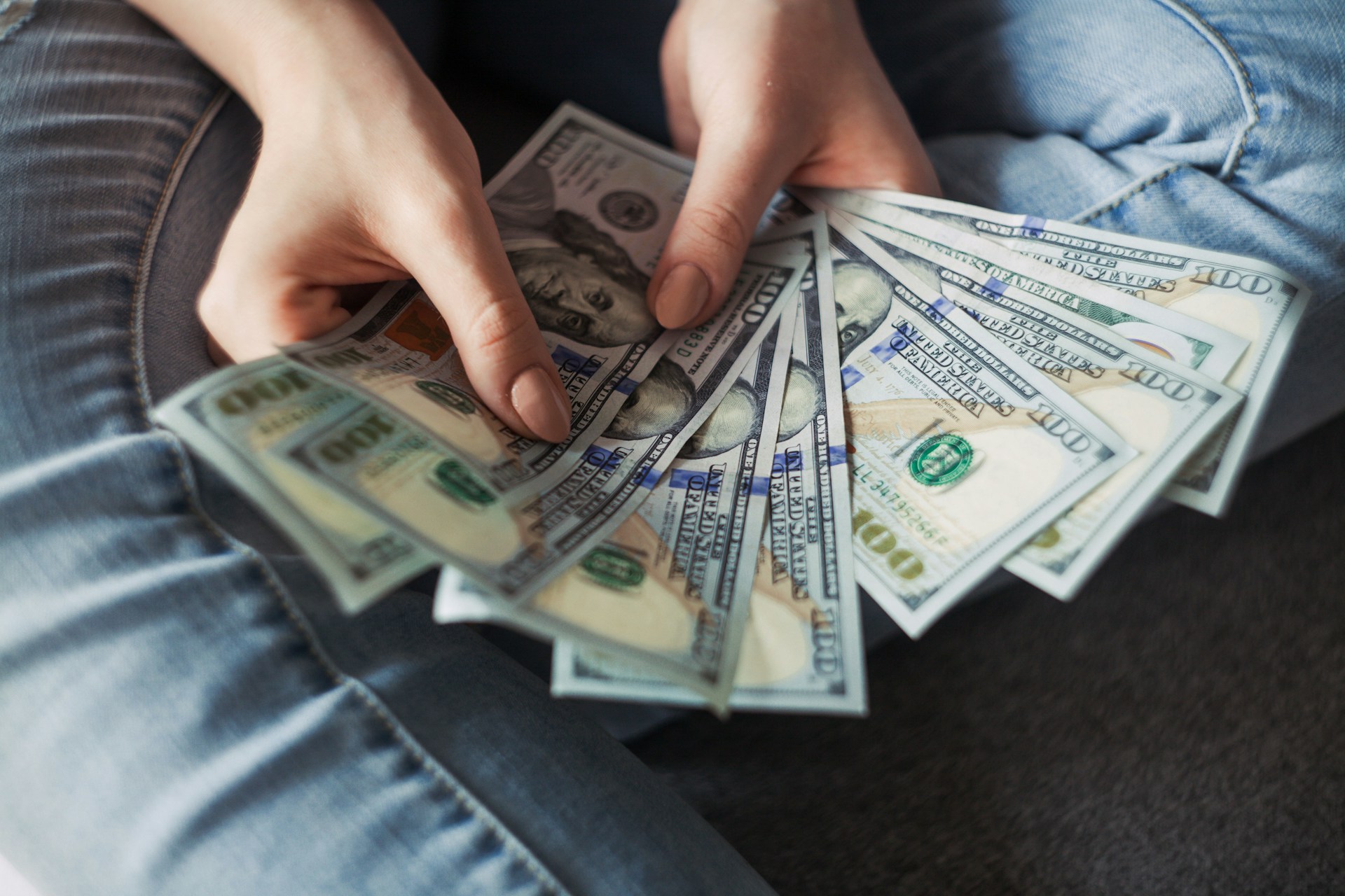 person holding a wad of 100 dollar bills in their hand