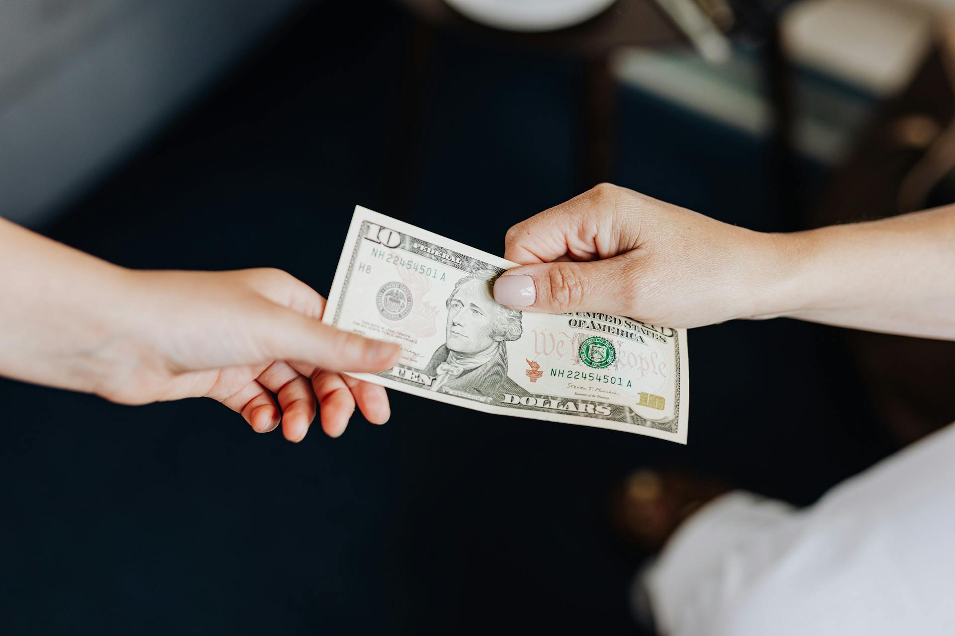 two people holding onto a dollar bill representing blog post about gold ira fees and a guide to understanding gold ira fees