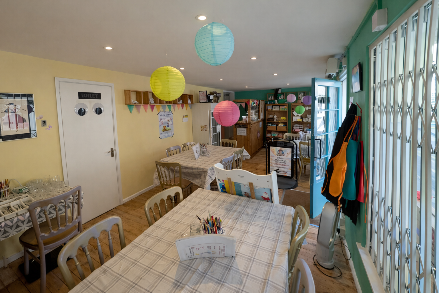 Inside The Crafty Beanie toddler craft class studio in Saffron Walden with tables set up for pottery painting and crafts.