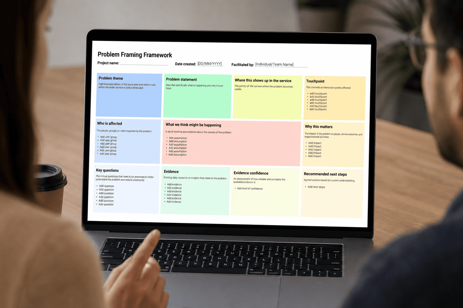 A woman and a man look at a laptop displaying a Problem Framing Framework