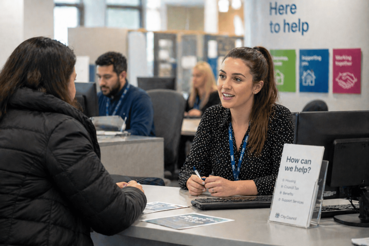 A woman in a black jacket talks with a smiling receptionist at a customer service desk