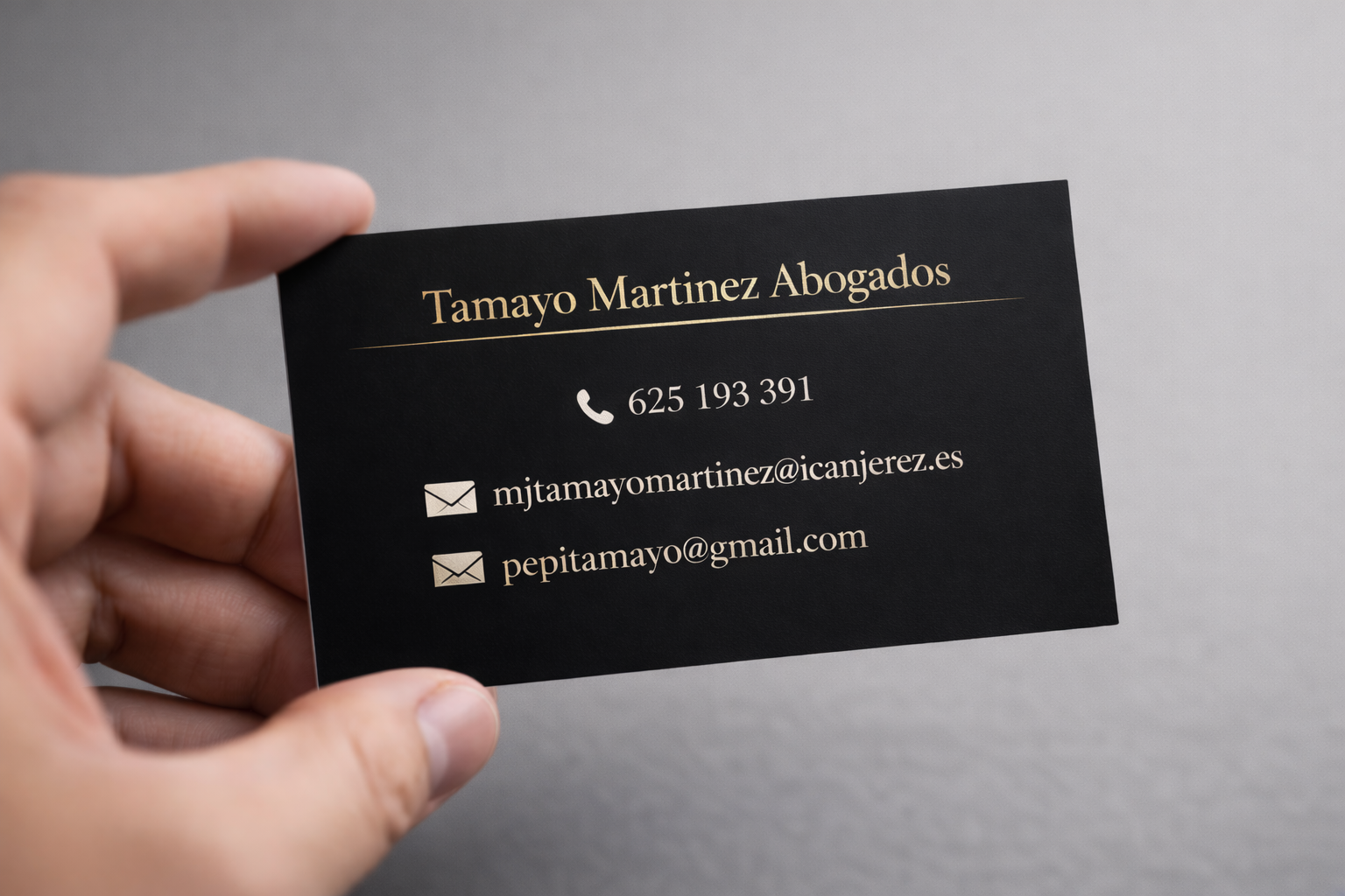 Mano sosteniendo una tarjeta de presentación profesional negra y dorada para el bufete de abogados T