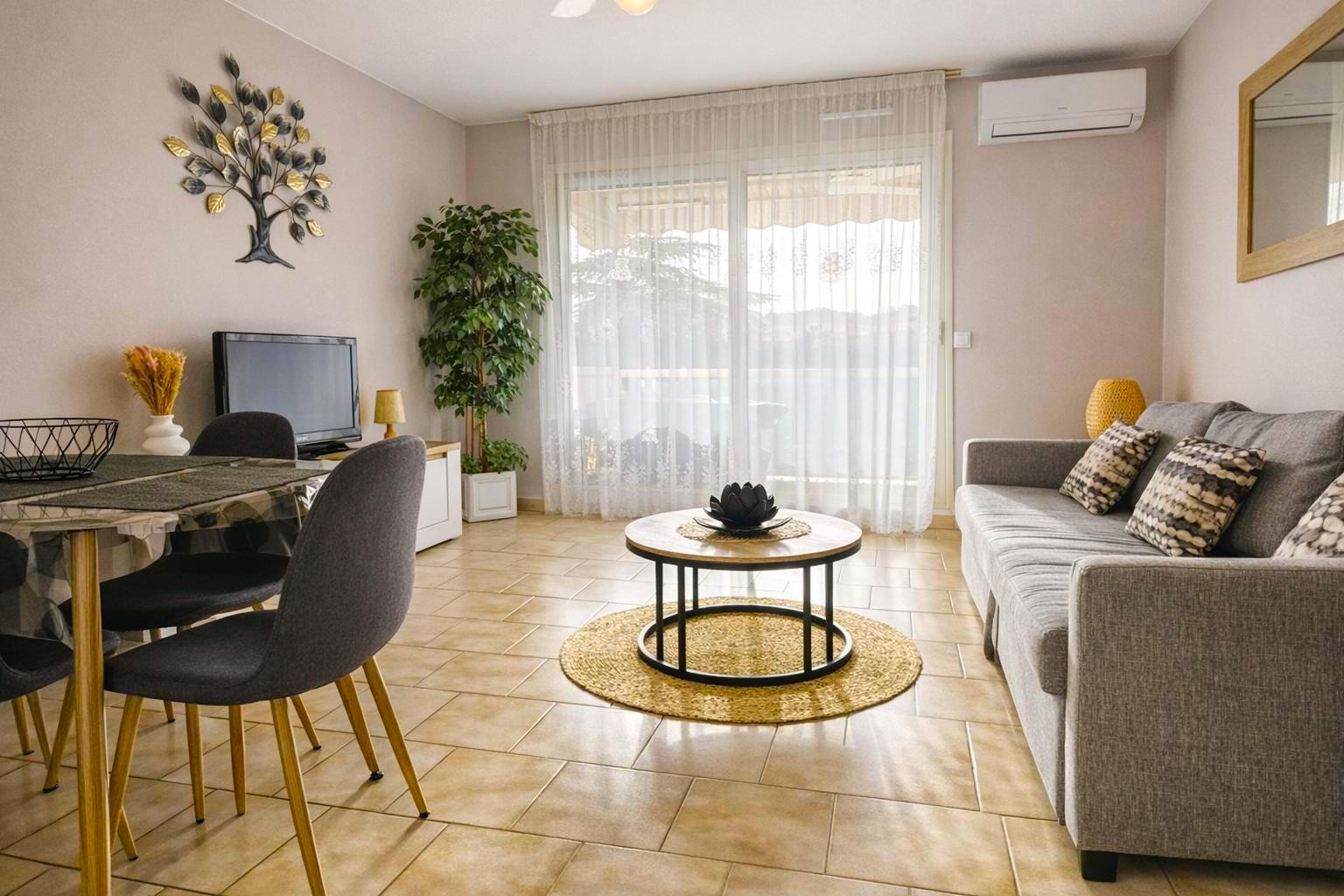 Salon moderne avec un canapé gris, une table basse ronde et une grande porte coulissante et rideaux