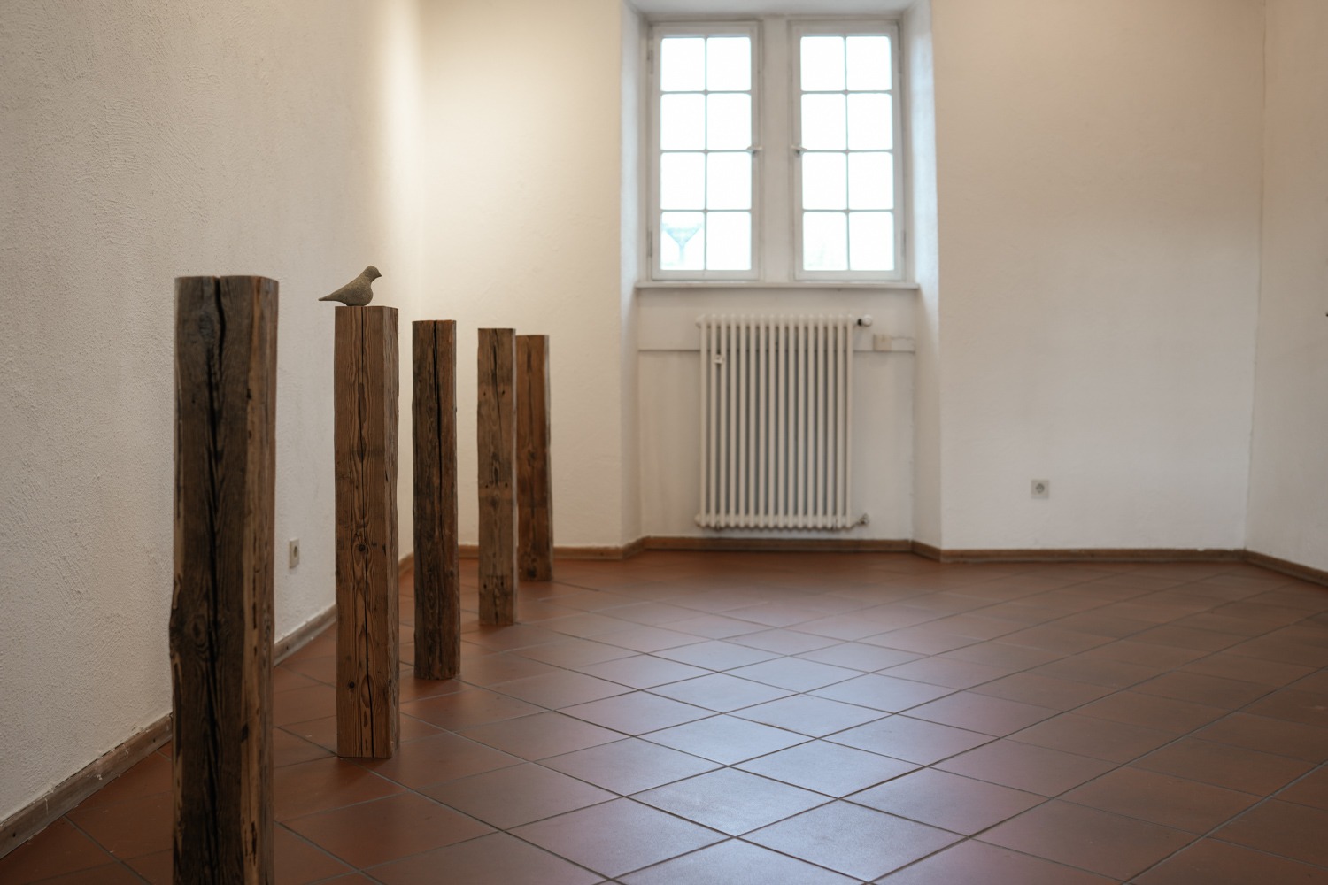 Still life with bird, 2024 - 1 ceramic bird, concrete, 5 wooden poles size variable ©Ties Ten Bosch