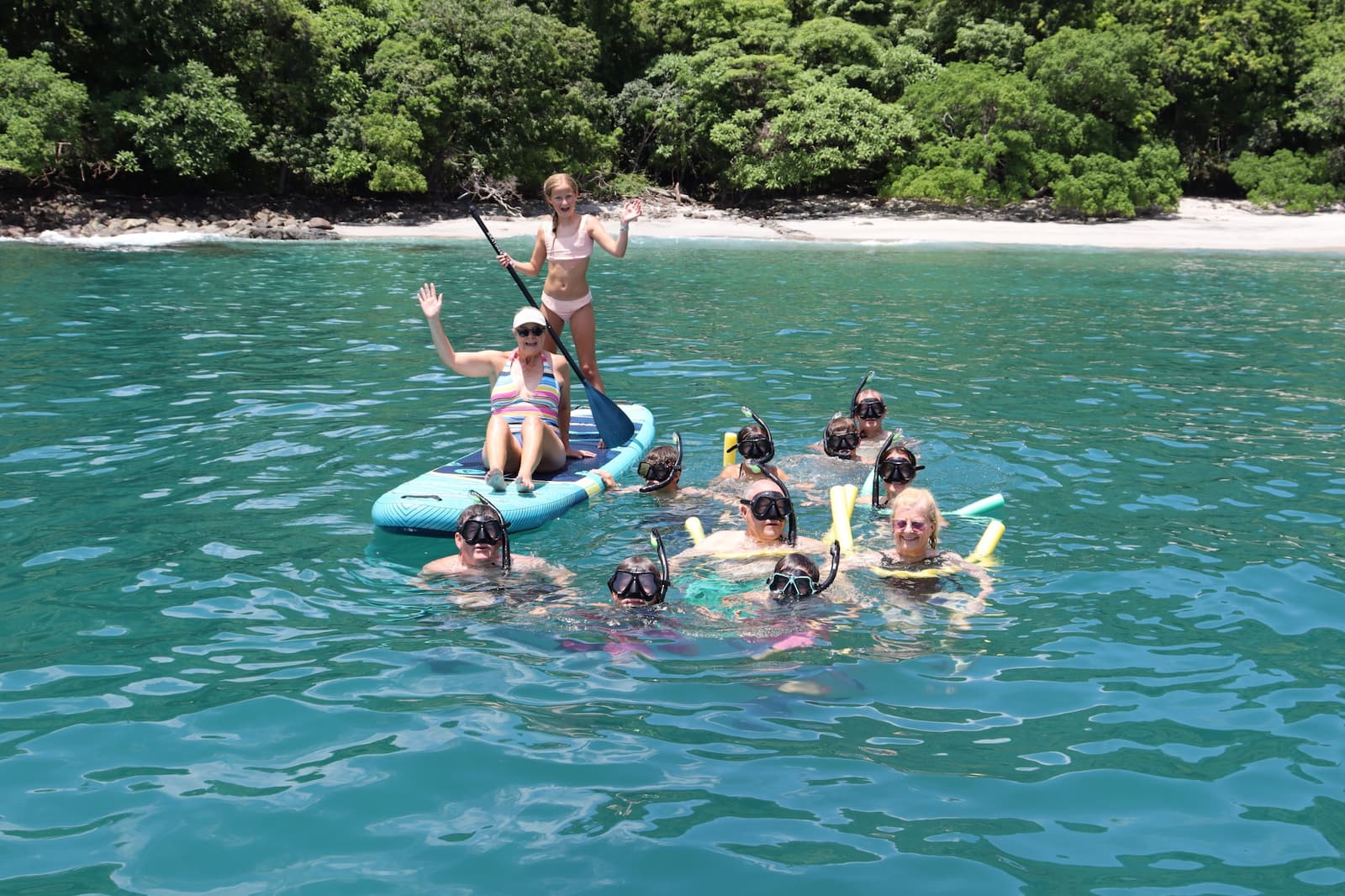Family enjoying snorkeling and paddle boards in turquoise waters during catamaran tour Papagayo
