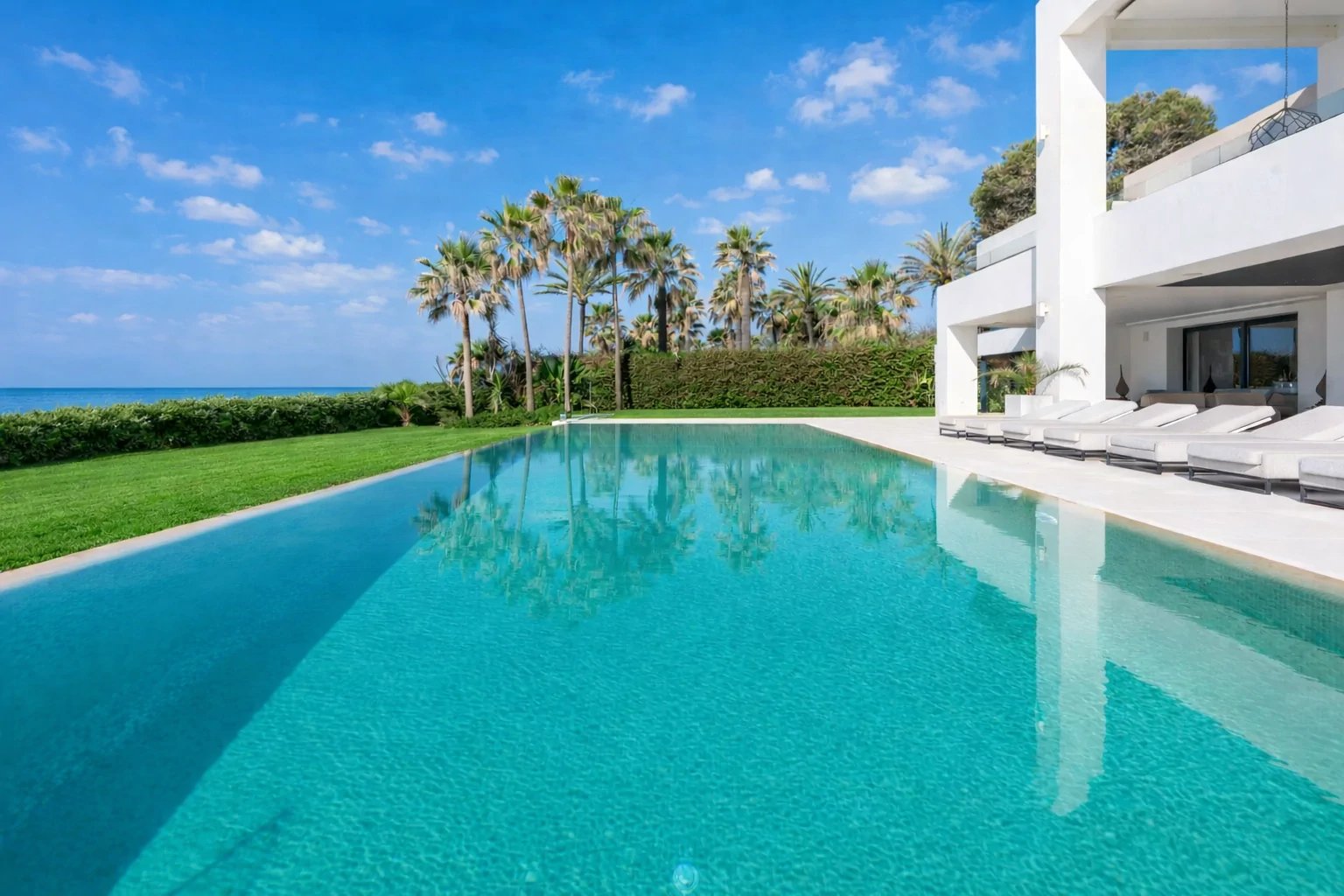 Beachfront infinity pool with palm lined gardens and sea views