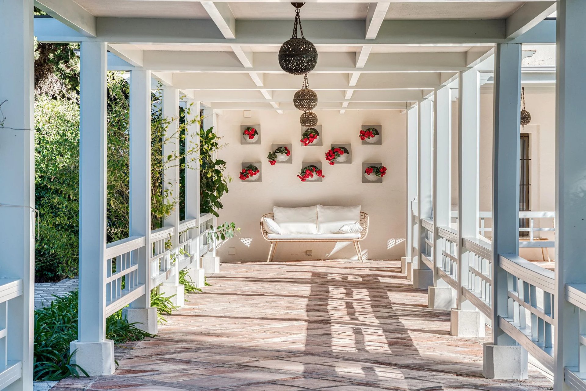 Shaded pergola walkway with lanterns and floral wall detail