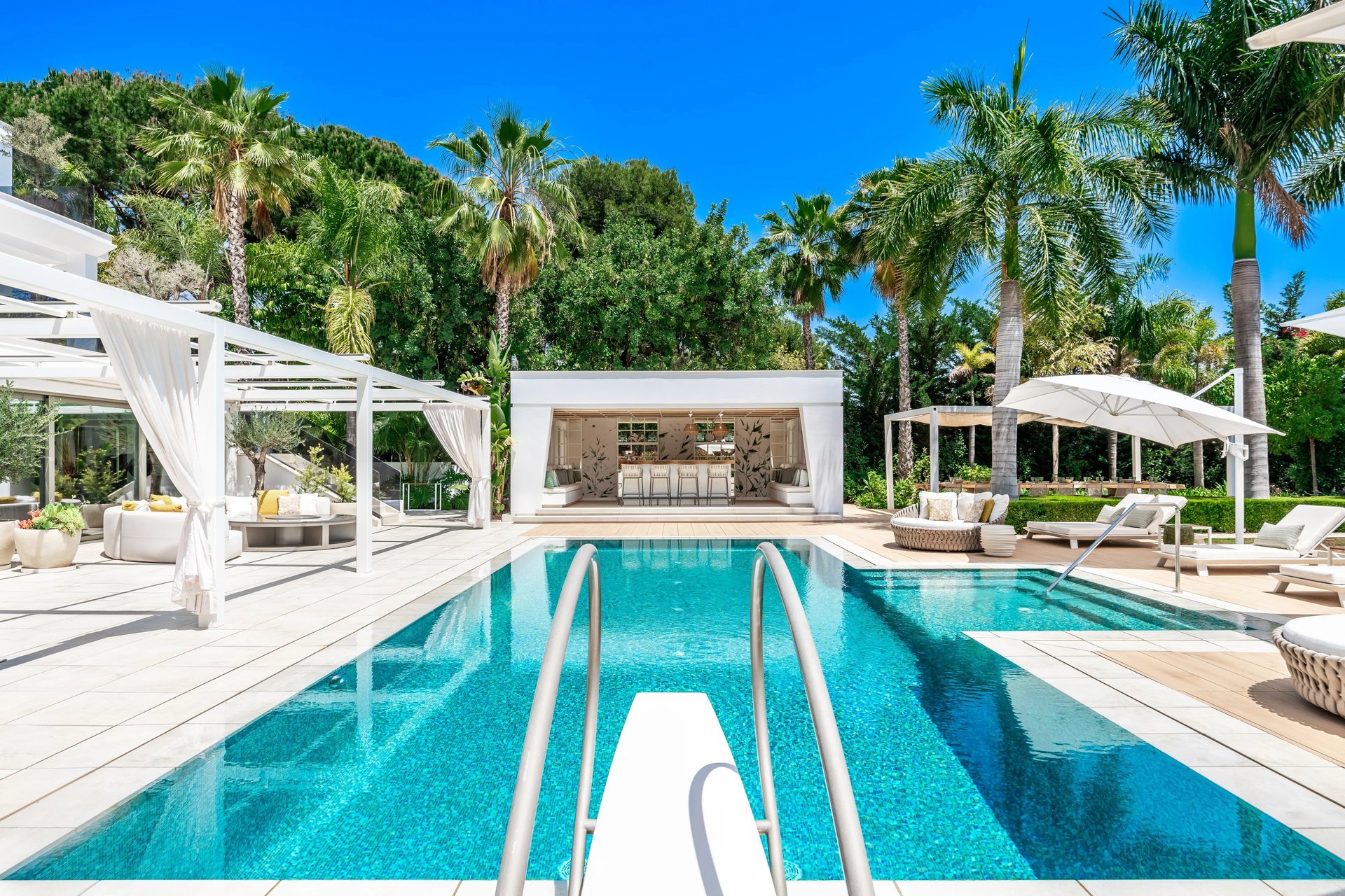 Long swimming pool with cabanas and palms