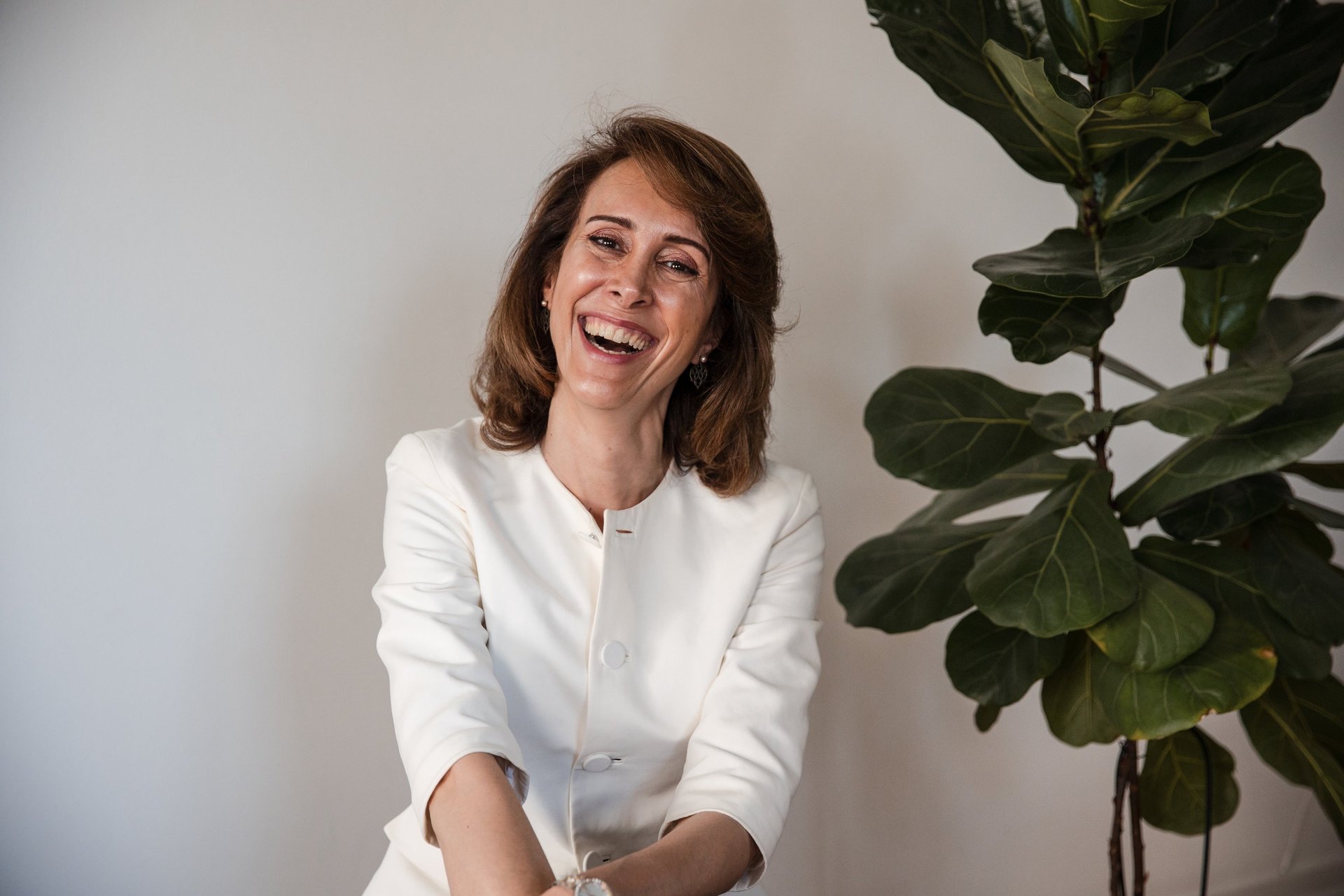 a female life coach in a white suit, smiling